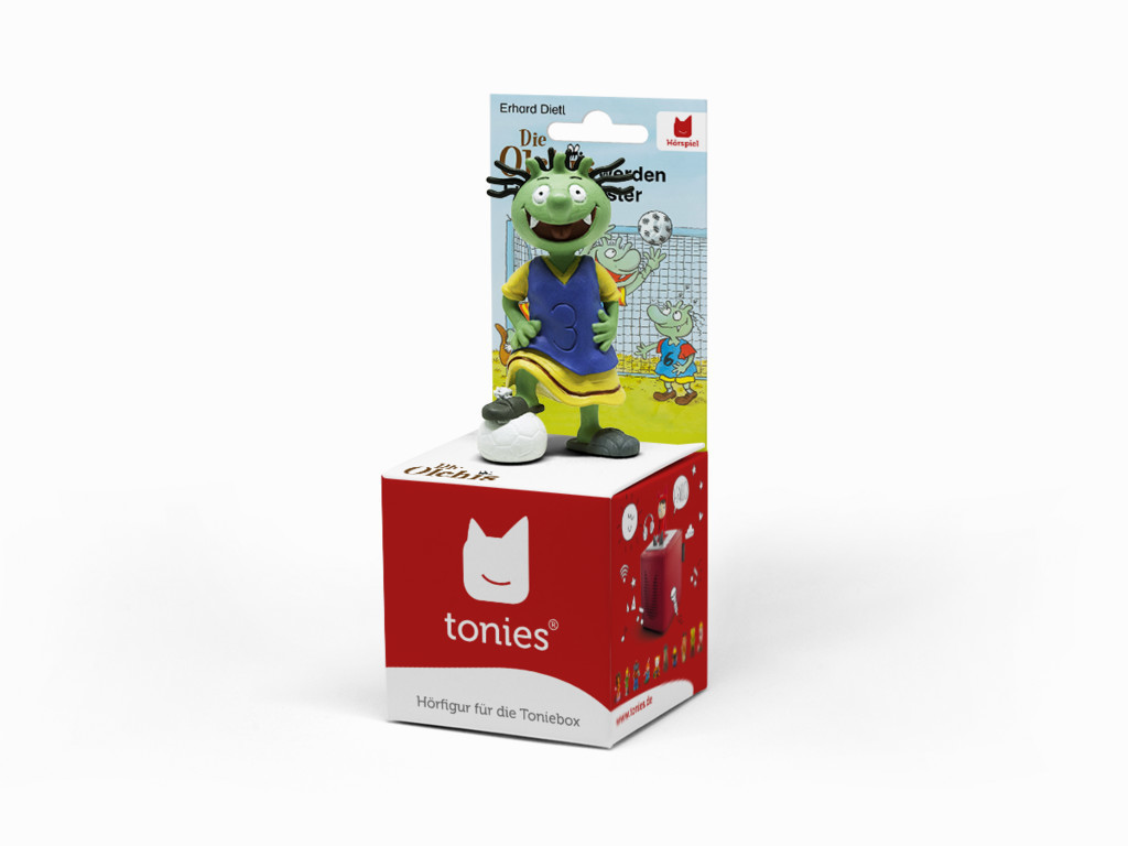 Eine Spielfigur eines grünen Monsters mit einem Fußball auf einer roten Box mit einem Cartoon.
