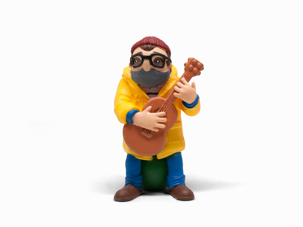 Eine kleine Figur eines Mannes, der Gitarre spielt, gelben Mantel und blaue Hose trägt.