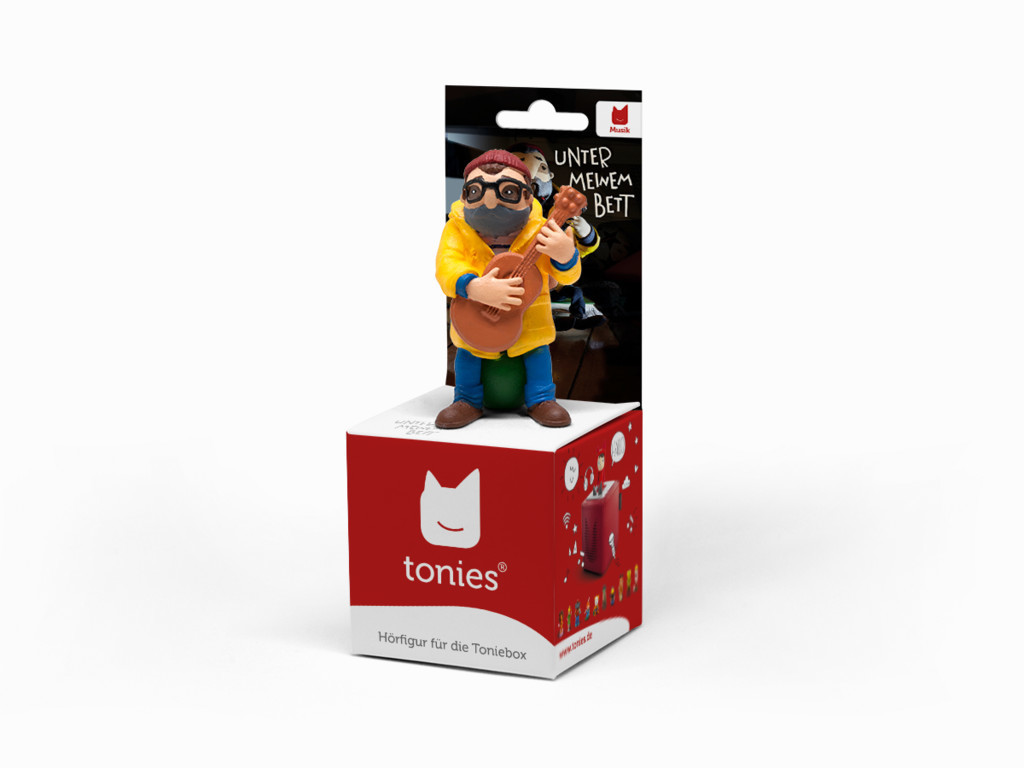 Eine Spielfigur eines Mannes, der Gitarre spielt, auf einem roten Würfel.