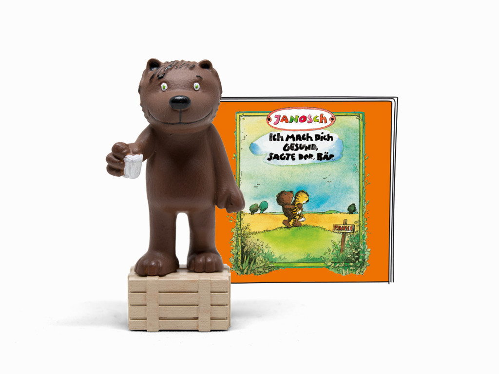 Bärenfigur, hält einen Becher, neben einem Buchcover.