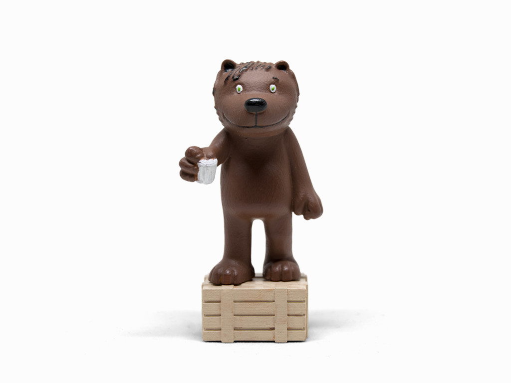 Braunbär-Figur auf Holzkiste mit Getränk, weißer Hintergrund.