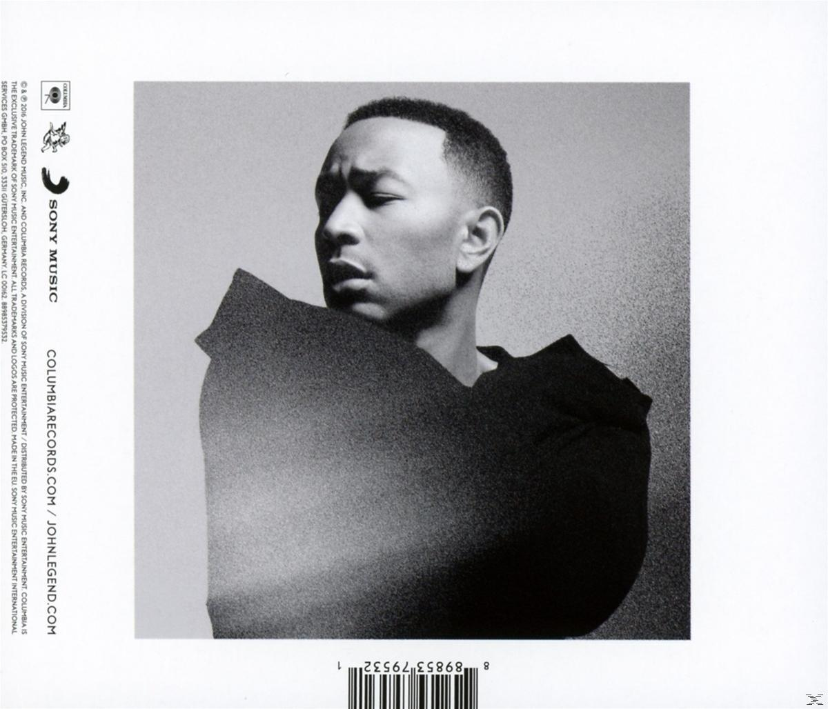 Schwarz-Weiß-Foto von John Legend. Er schaut zur Seite und trägt ein schwarzes Oberteil. Columbia Records- und Sony Music-Logos sind sichtbar.
