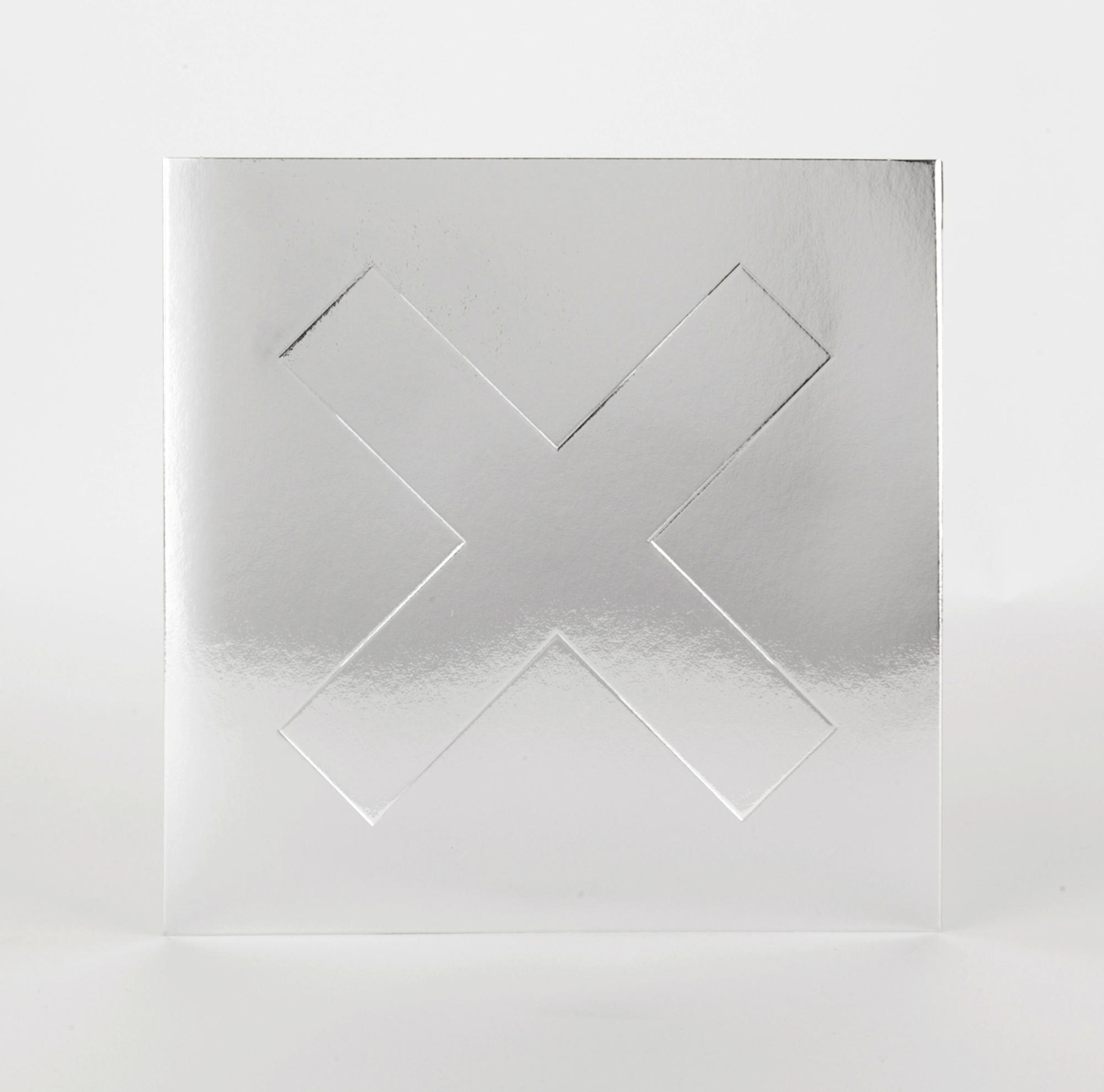 Silbernes Quadrat mit einem eingeschnittenen X. Das X ist leicht erhaben.