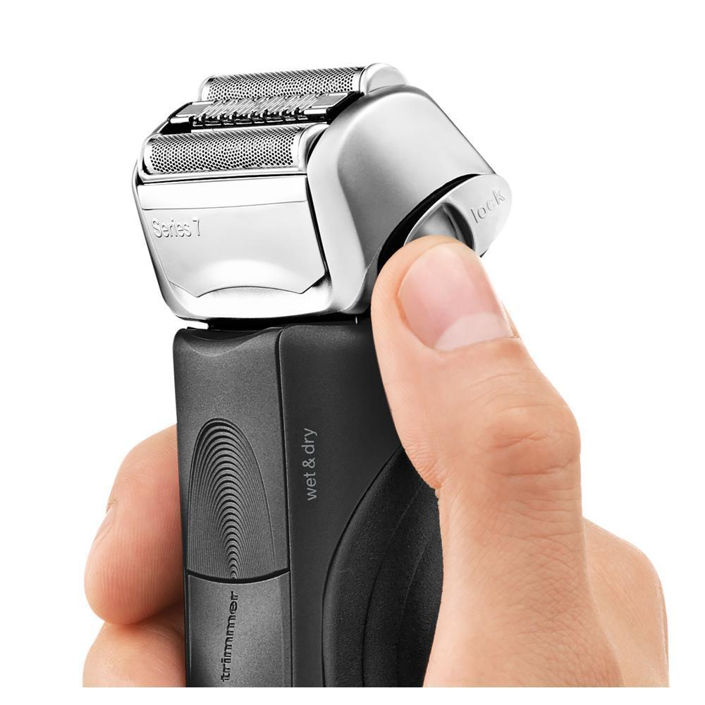Eine Person, die einen schwarz-silbernen Elektrorasierer der Serie 7 hält, mit einem Finger auf dem Schloss.