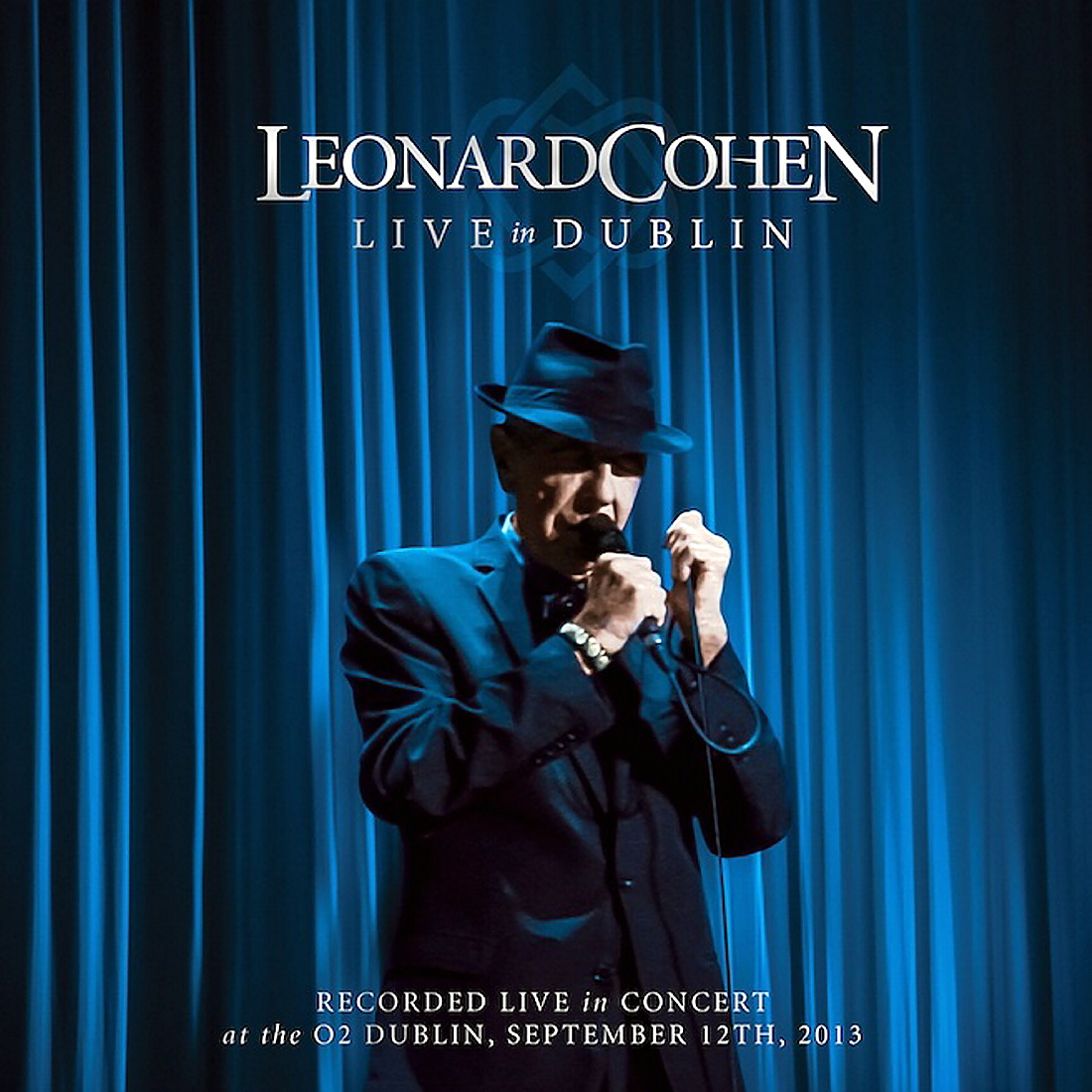 Albumhoes van Leonard Cohen op het podium, zingend in een microfoon. Tekst: Leonard Cohen Live in Dublin.