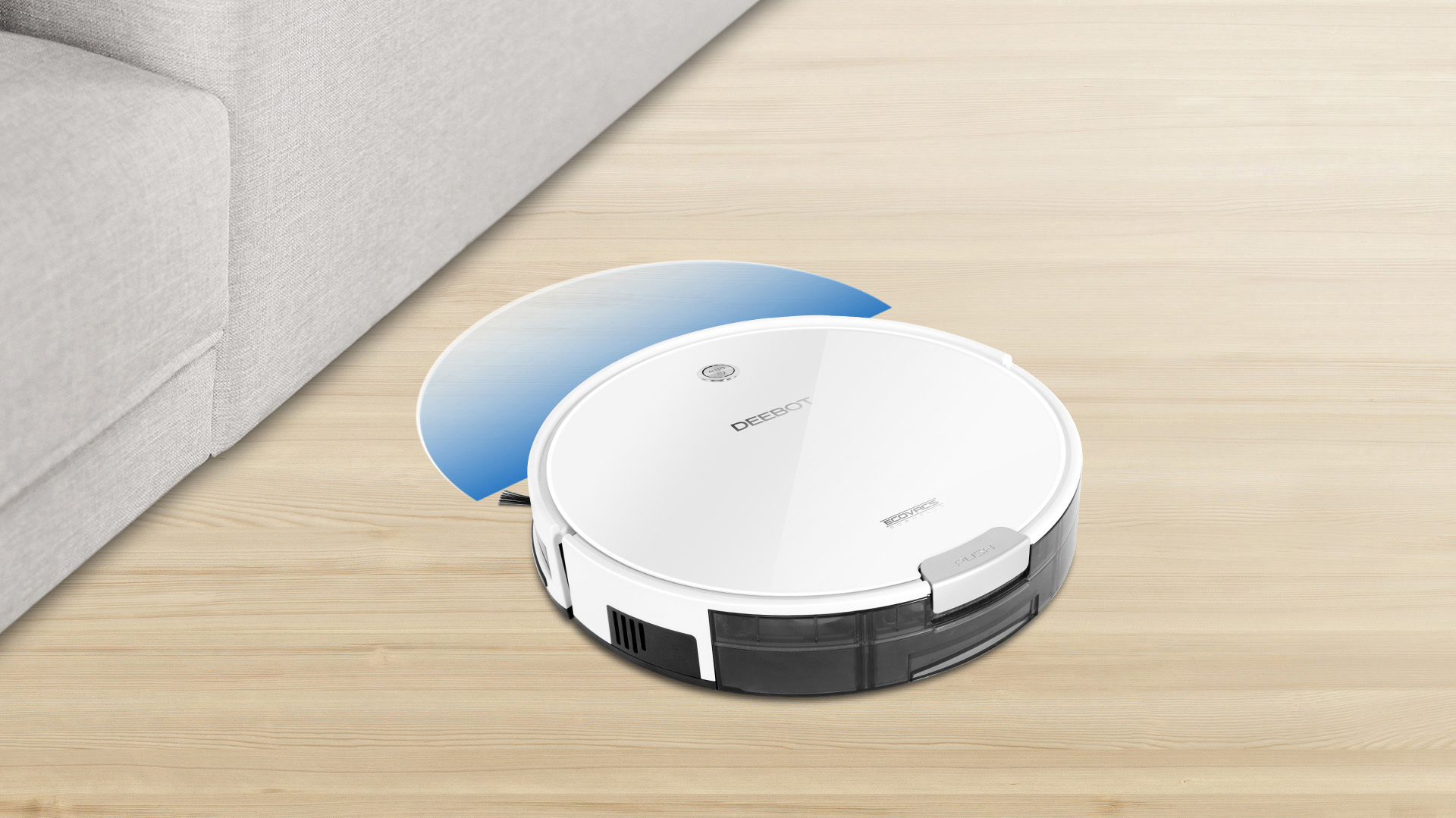 Ein weißer Roboter-Staubsauger auf einem Holzboden neben einem grauen Sofa. Der Staubsauger zeigt einen blauen Reinigungspfad.