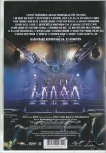DVD-Cover mit einer Band auf der Bühne. Bühnenbeleuchtung und eine große Leinwand im Hintergrund.