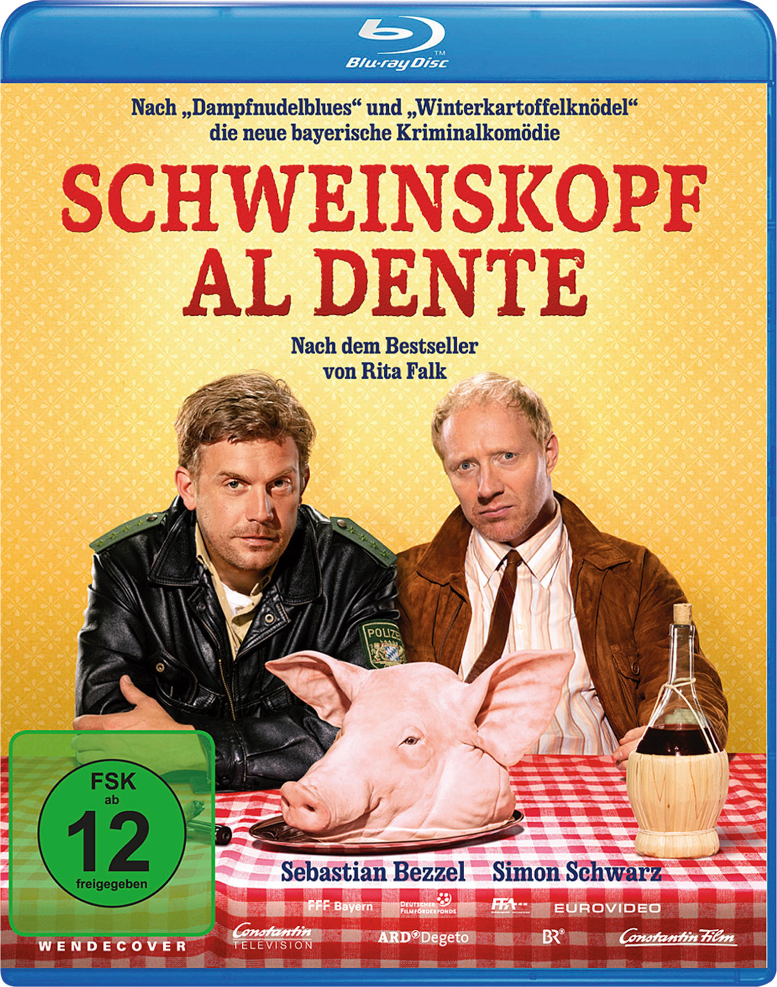 Filmcover 'Schweinskopf Al Dente', mit zwei Männern und einem Schwein auf einem Tisch mit einer Weinflasche.
