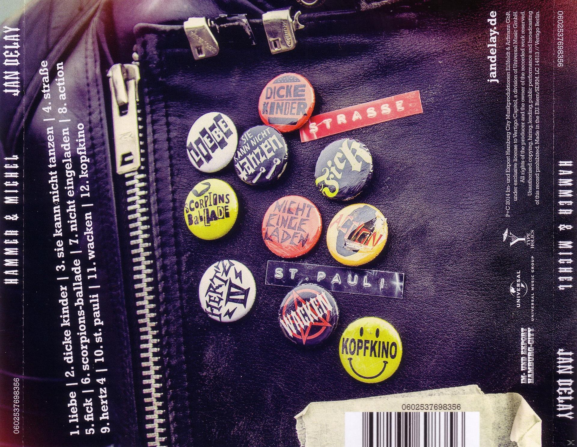 Nahaufnahme einer schwarzen Lederjacke mit Knöpfen, Etiketten und Text, darunter die Worte 'St. Pauli' und 'Kopfkino'.