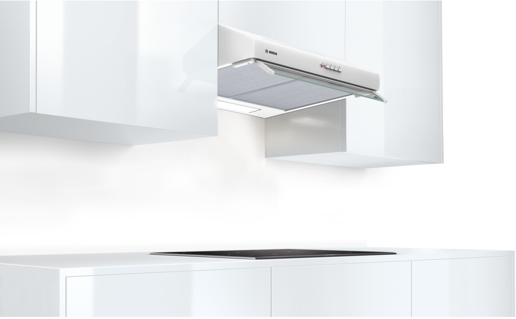 A white kitchen hood is mounted between two white cabinets, a black stove is below.