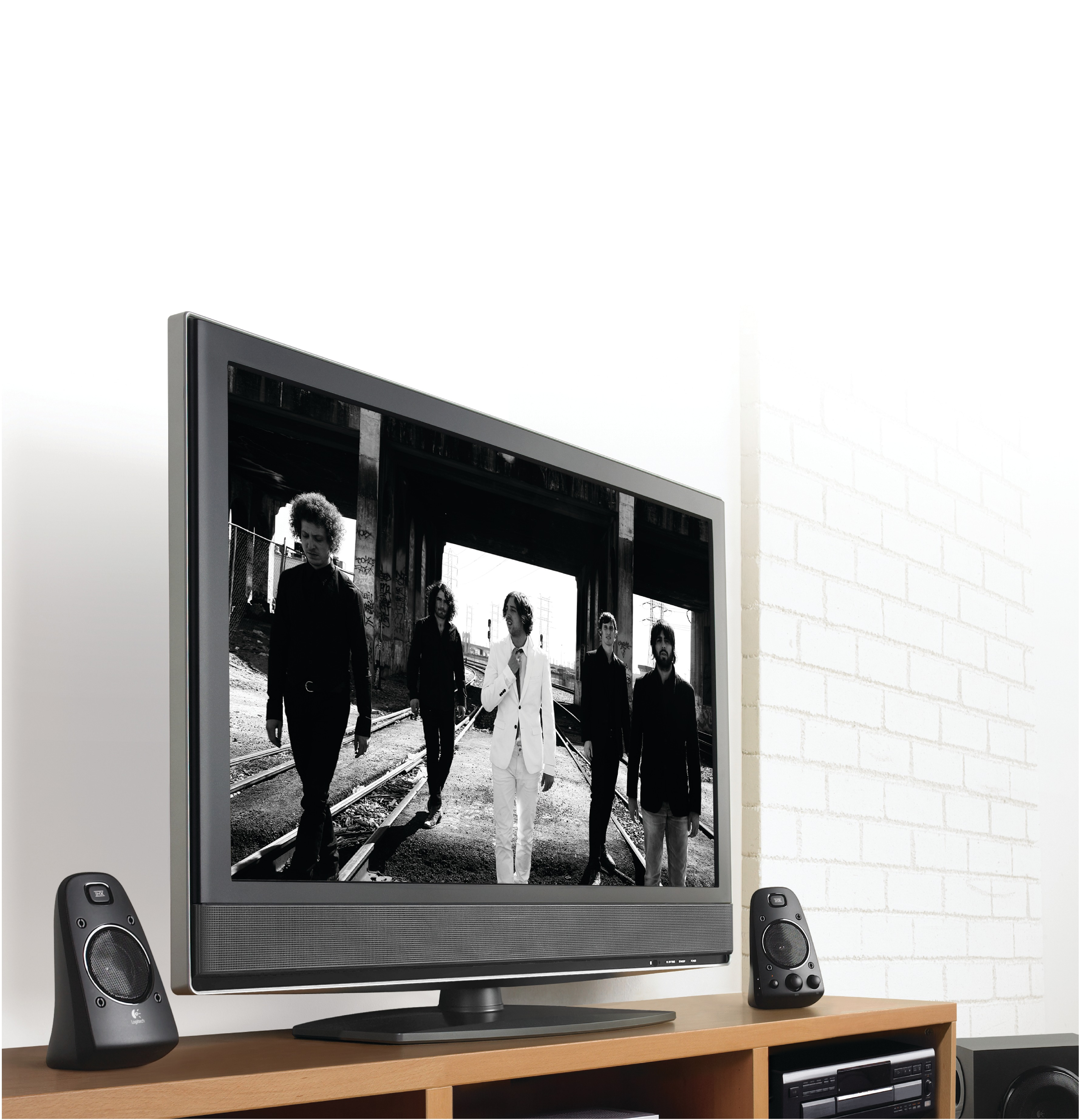 Black and white image on a TV screen. Speakers on either side. Wooden table and white wall.