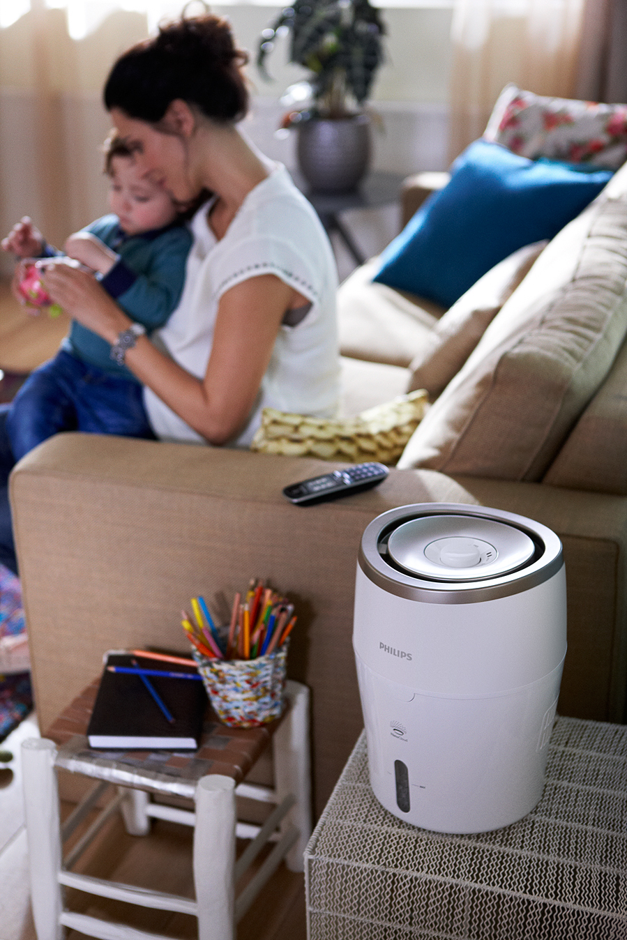 Szene einer Mutter und eines Kindes mit einem Philips Luftreiniger. Ein kleiner Tisch mit Gegenständen in der Nähe.