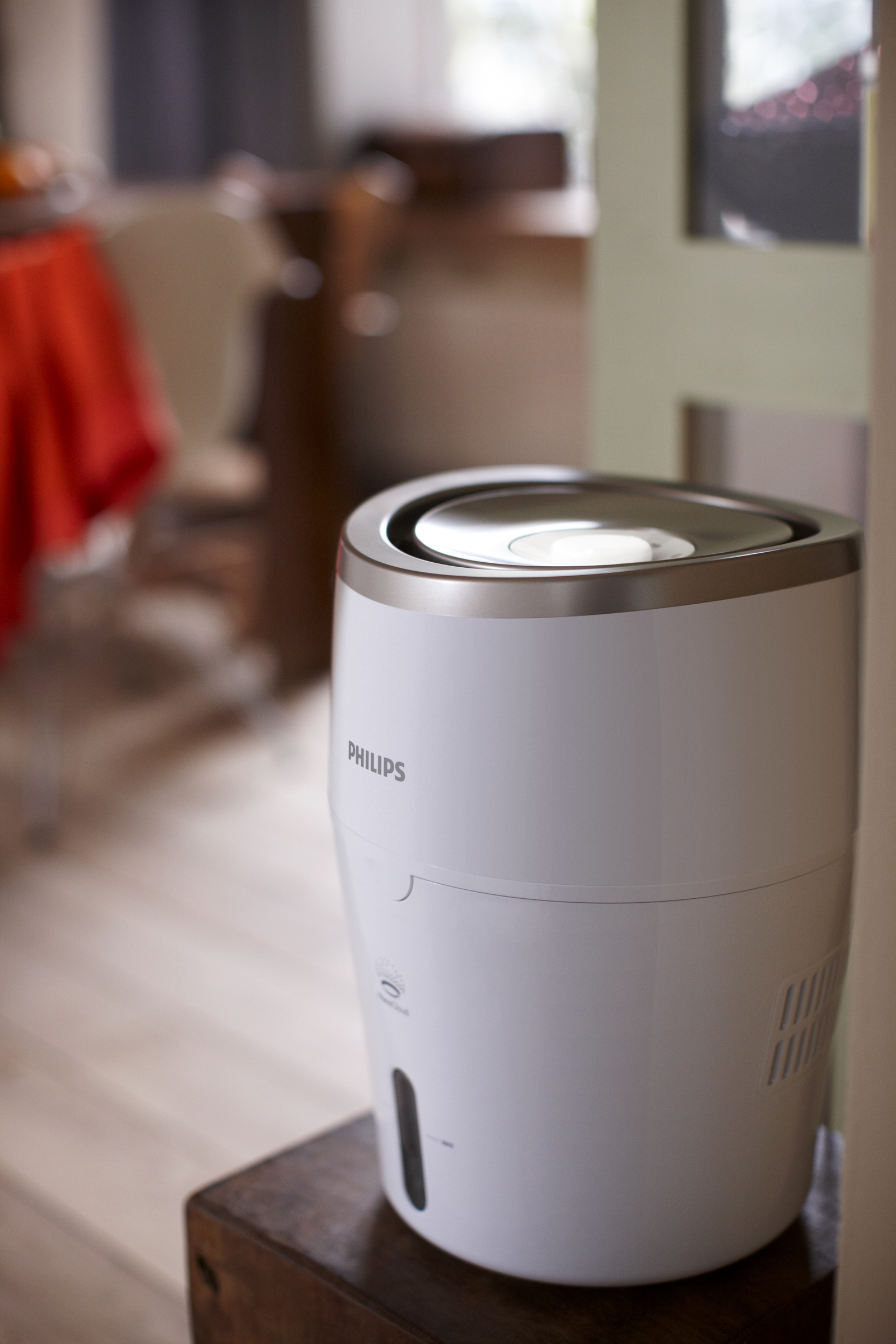Ein weißer Philips Luftbefeuchter auf einem Holzständer in einem Raum.