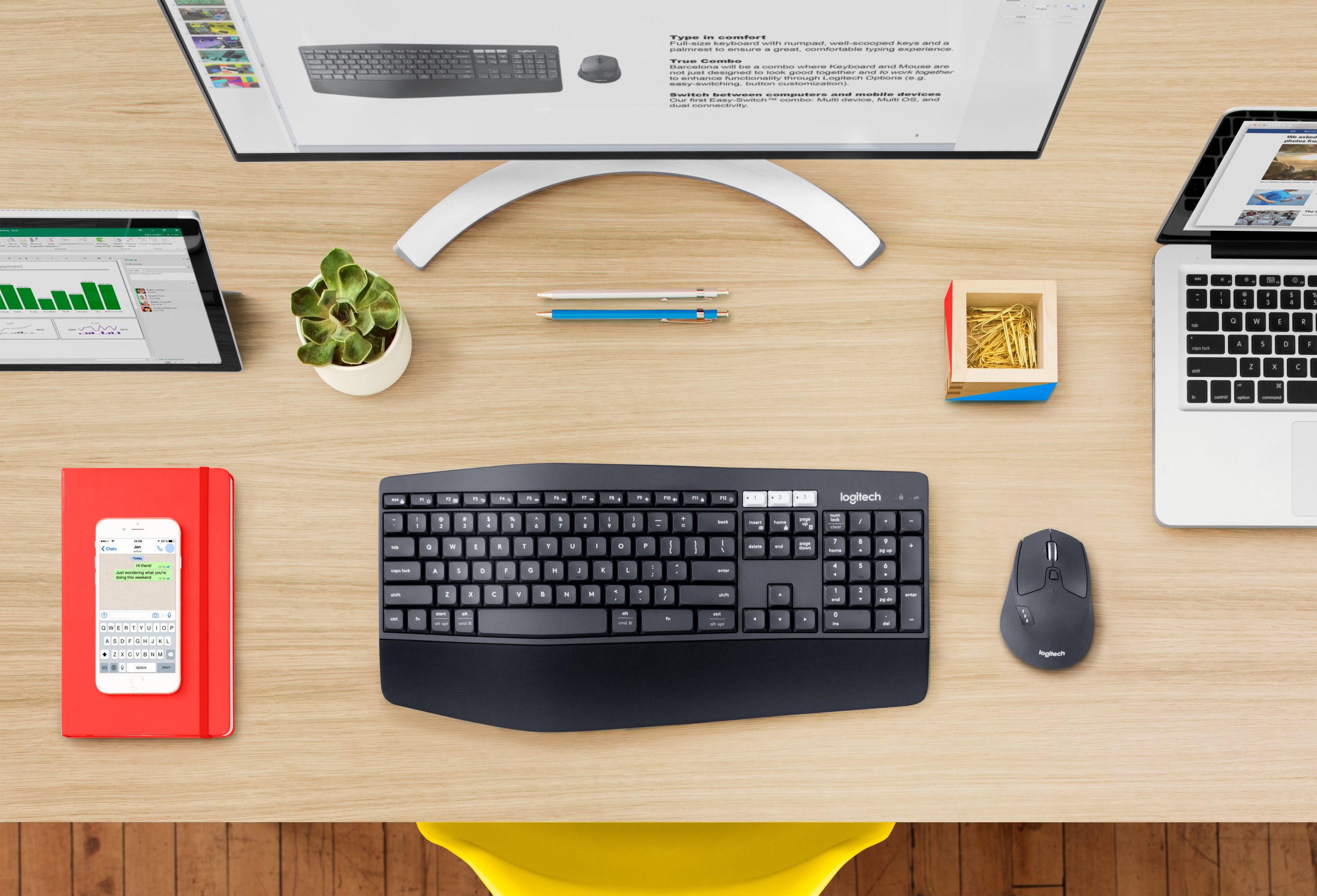 Overhead view of a desk setup with a keyboard, mouse, monitor, laptop, and notepad.