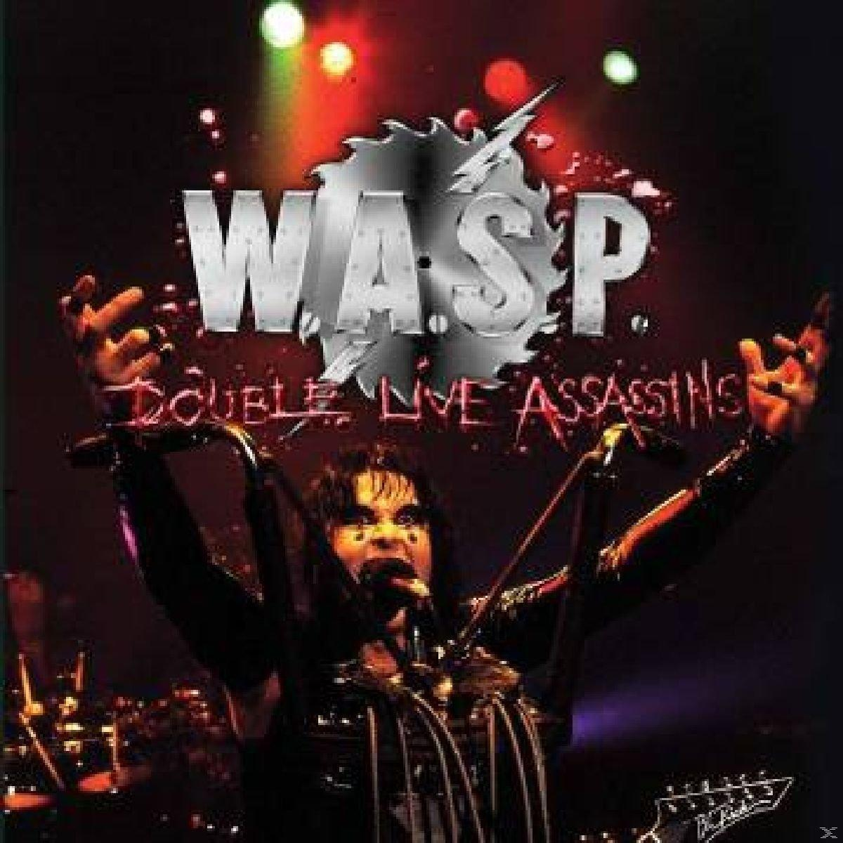 Albumcover. Mann mit Make-up, Arme erhoben, singend. Titel 'Double Live Assassins'. Dunkler Bühnenhintergrund.
