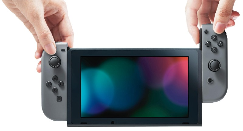 Hände halten graue Controller, die mit einer Nintendo Switch mit farbenfrohem Bildschirm verbunden sind.