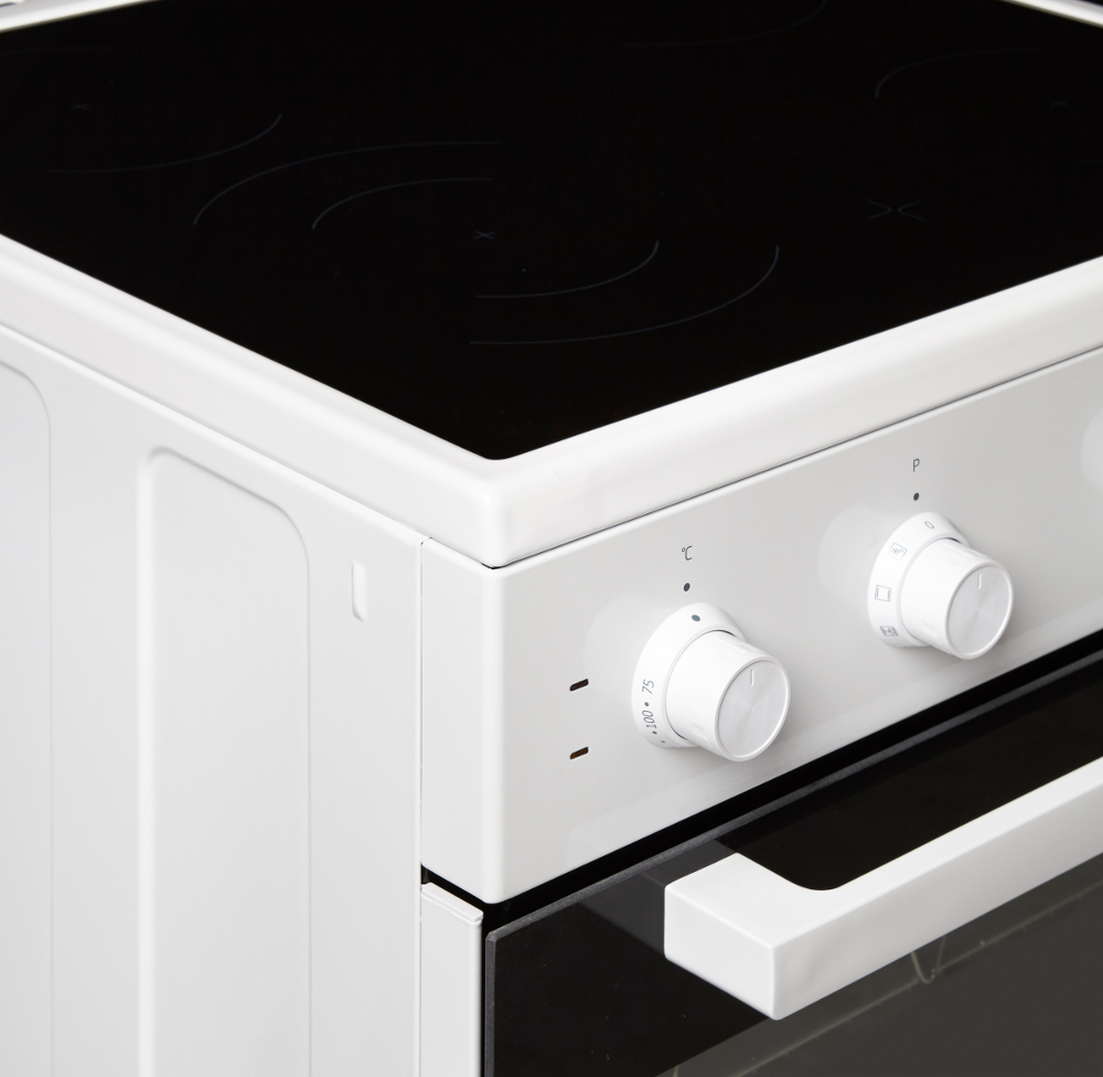 Close-up of a white oven-stove with black stovetop and white knobs.