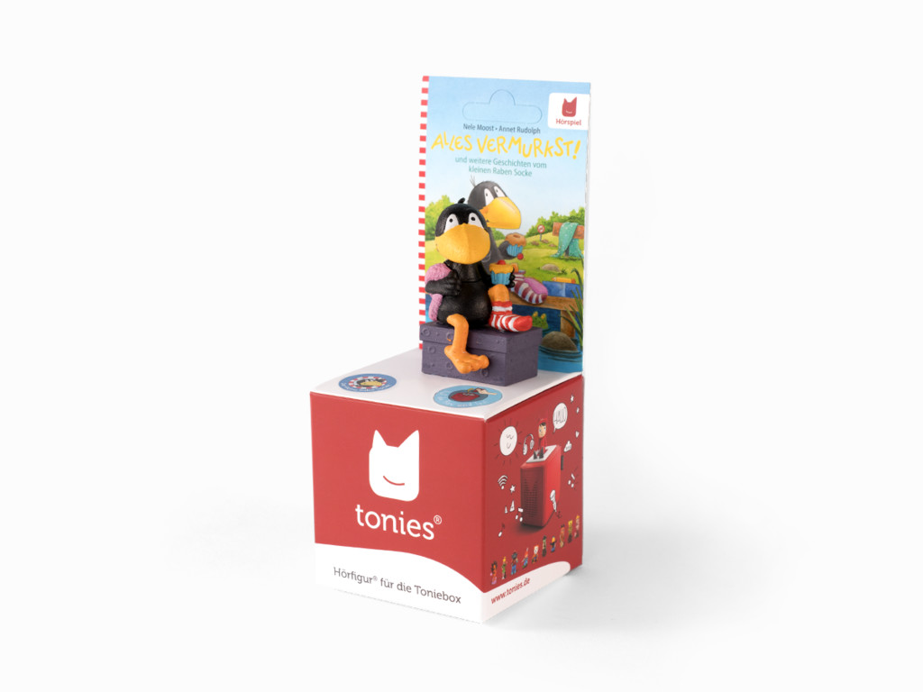 Eine Vogelfigur auf einer roten Box. Ein Buch mit einem Cartoon-Vogel ist dahinter.