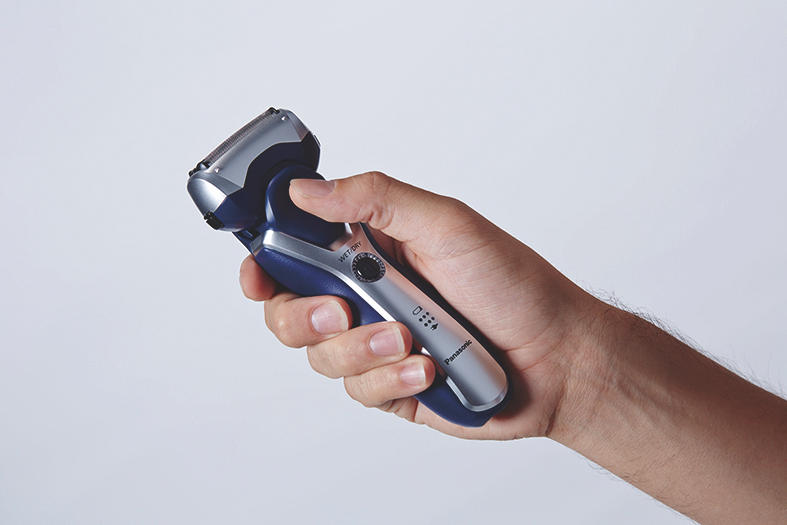 Hand hält einen Elektrorasierer. Blaues und silbernes Design. Weißer Hintergrund.