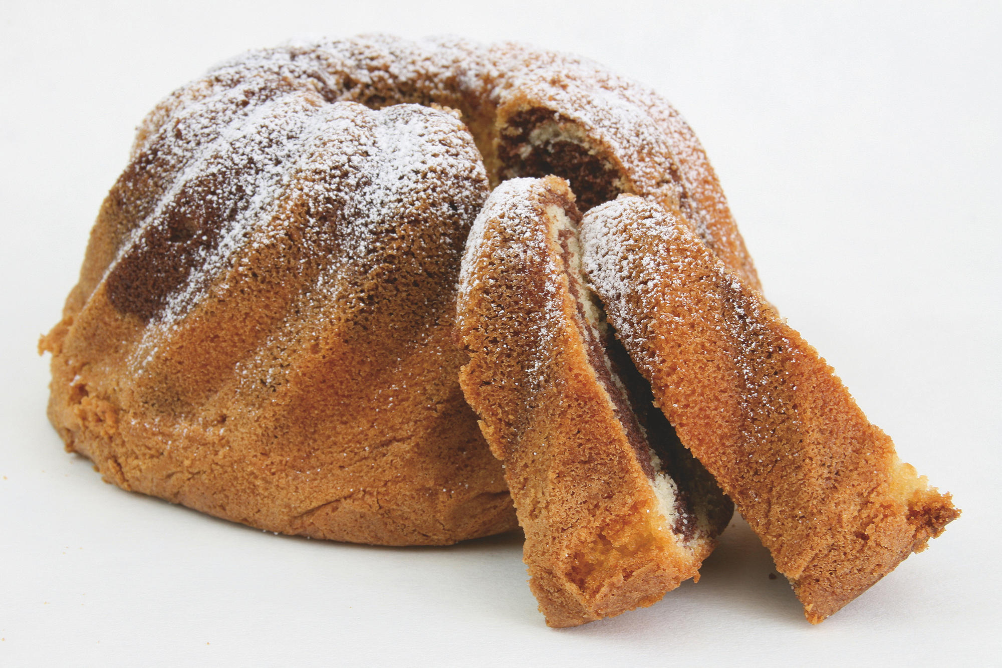 Marmorkuchen mit Puderzucker und geschnittenen Scheiben auf weißer Oberfläche.