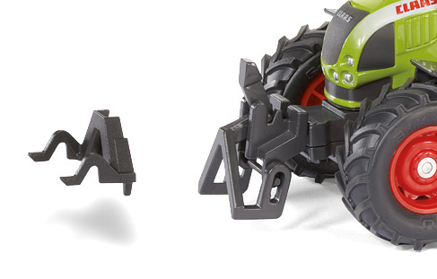 Ein schwarzes Traktoranbaugerät und ein grüner und schwarzer Spielzeugtraktor mit roten Rädern vor weißem Hintergrund.