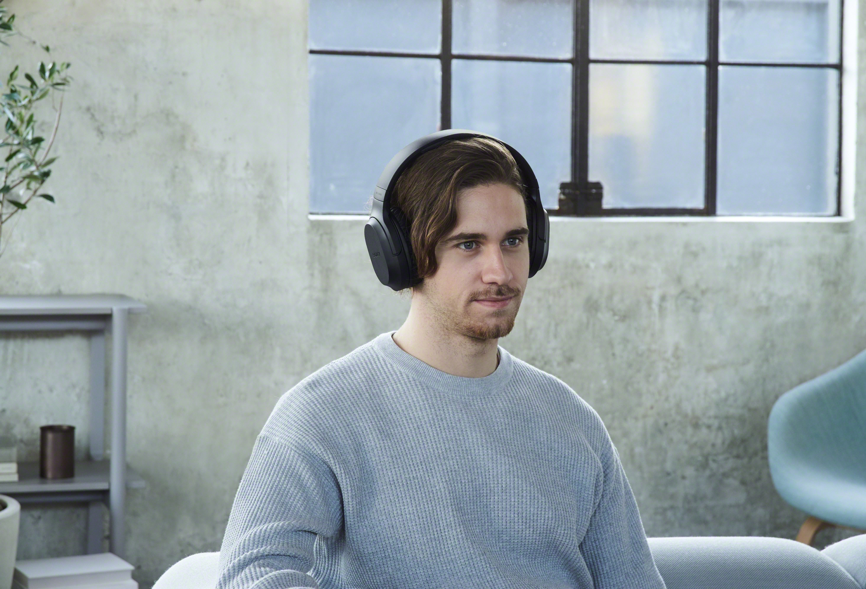 Homme portant un casque, à l'intérieur, regardant vers la droite, pull gris clair.