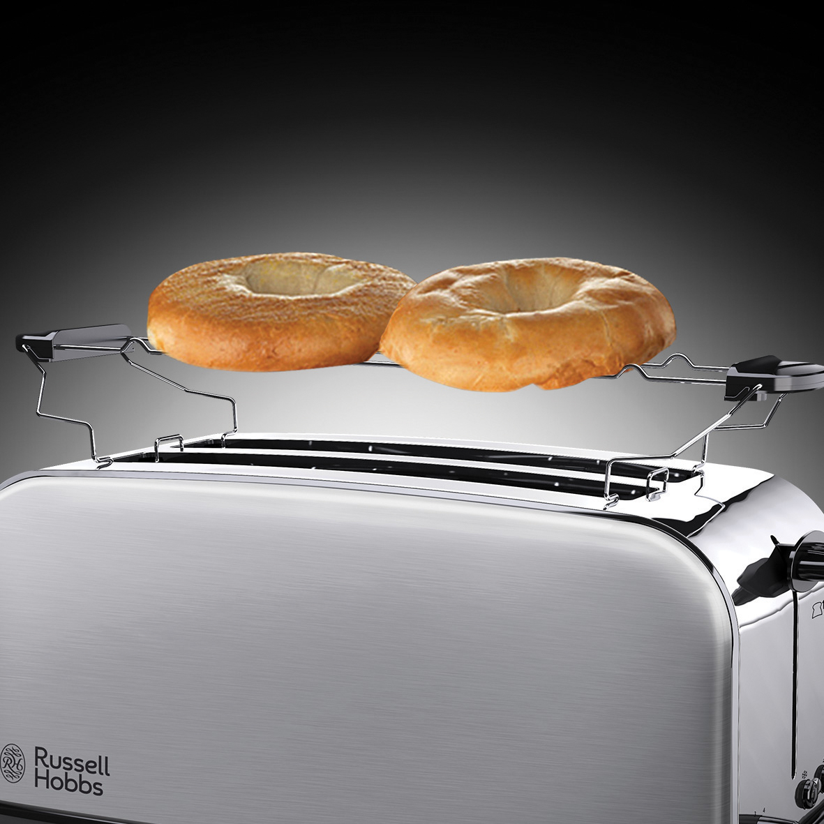 A silver toaster with two bagels being toasted.
