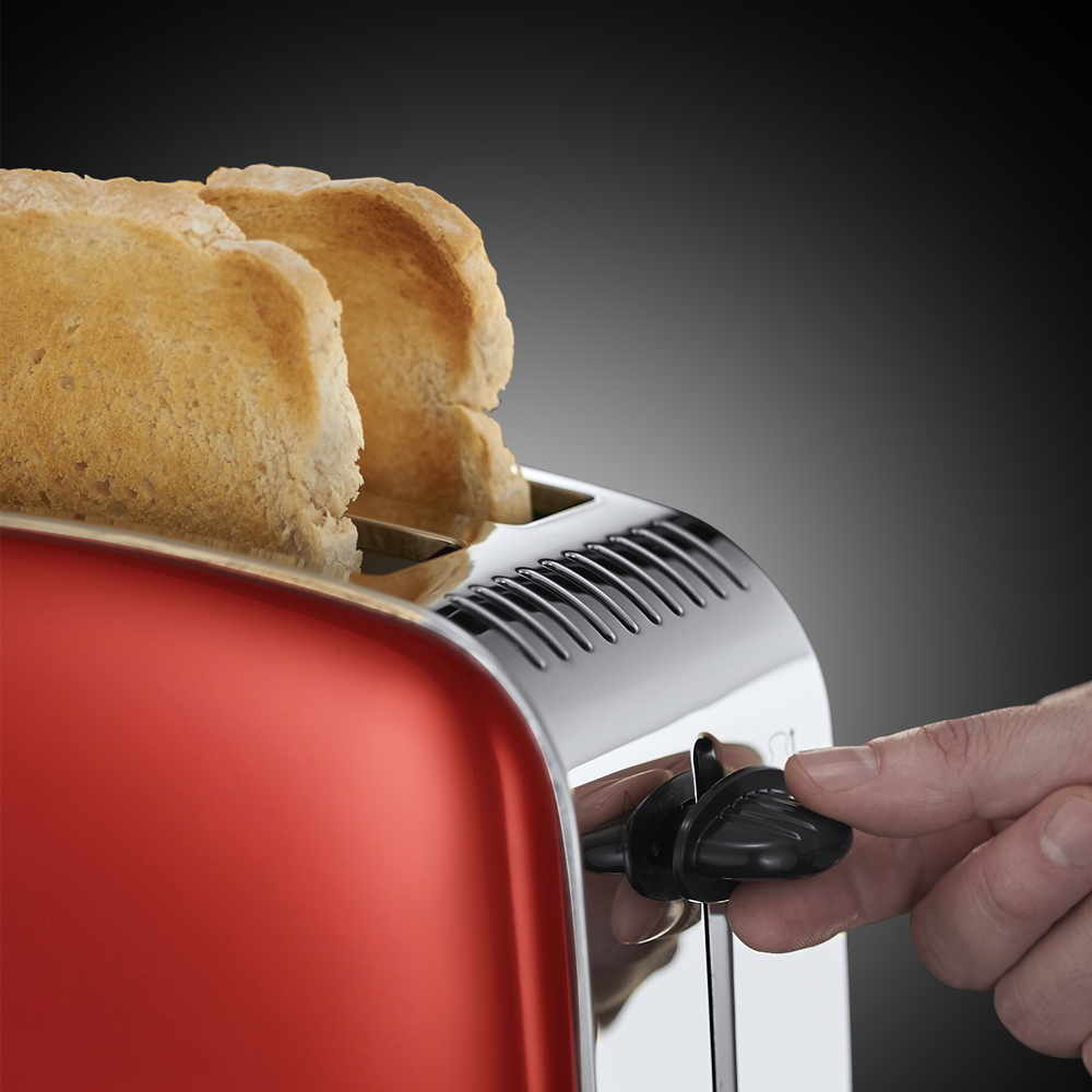 Een rode broodrooster met twee sneetjes toast. Een hand past de bruiningsregelaar aan.