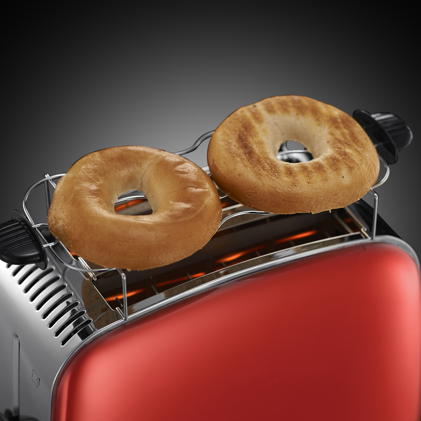 Rode broodrooster met twee geroosterde bagels op het warmhoudrooster, warm licht.