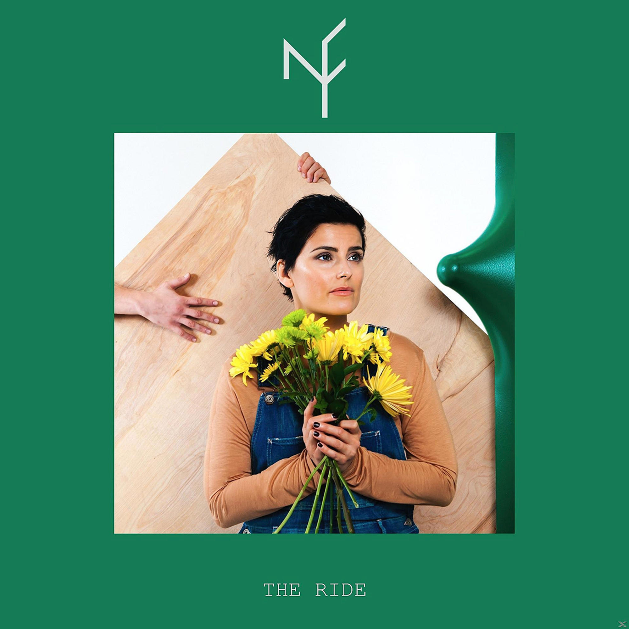 Een vrouw houdt gele bloemen vast, met hout en groene vormen op de achtergrond. Handen op hout. Groene rand met tekst 'THE RIDE'.