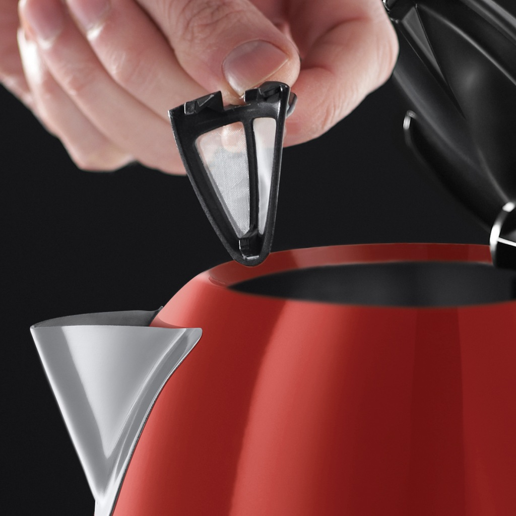 A hand is holding a black filter from a red and silver electric kettle.