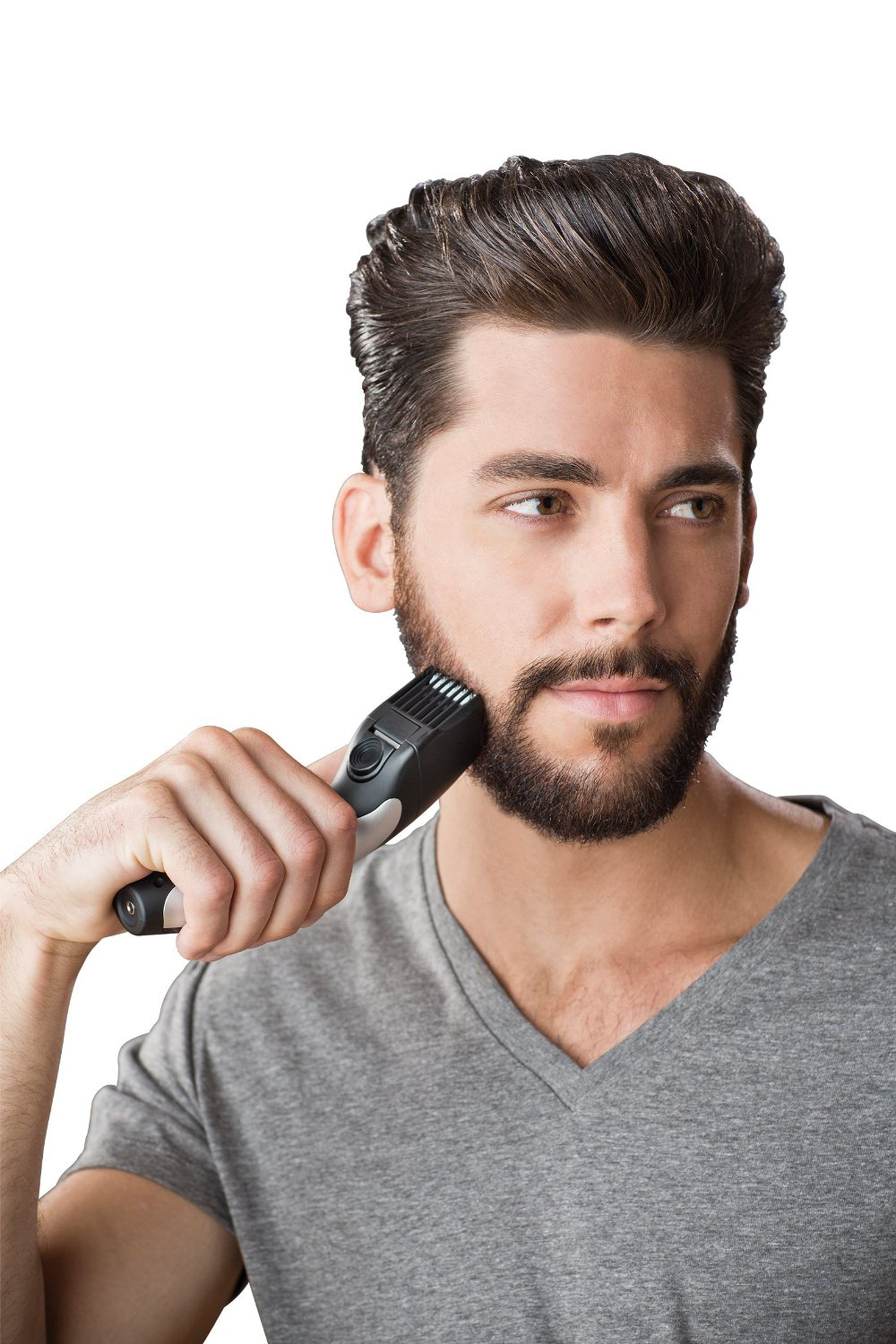 Ein Mann rasiert seinen Bart mit einem Trimmer. Er schaut zur Seite mit konzentriertem Blick.