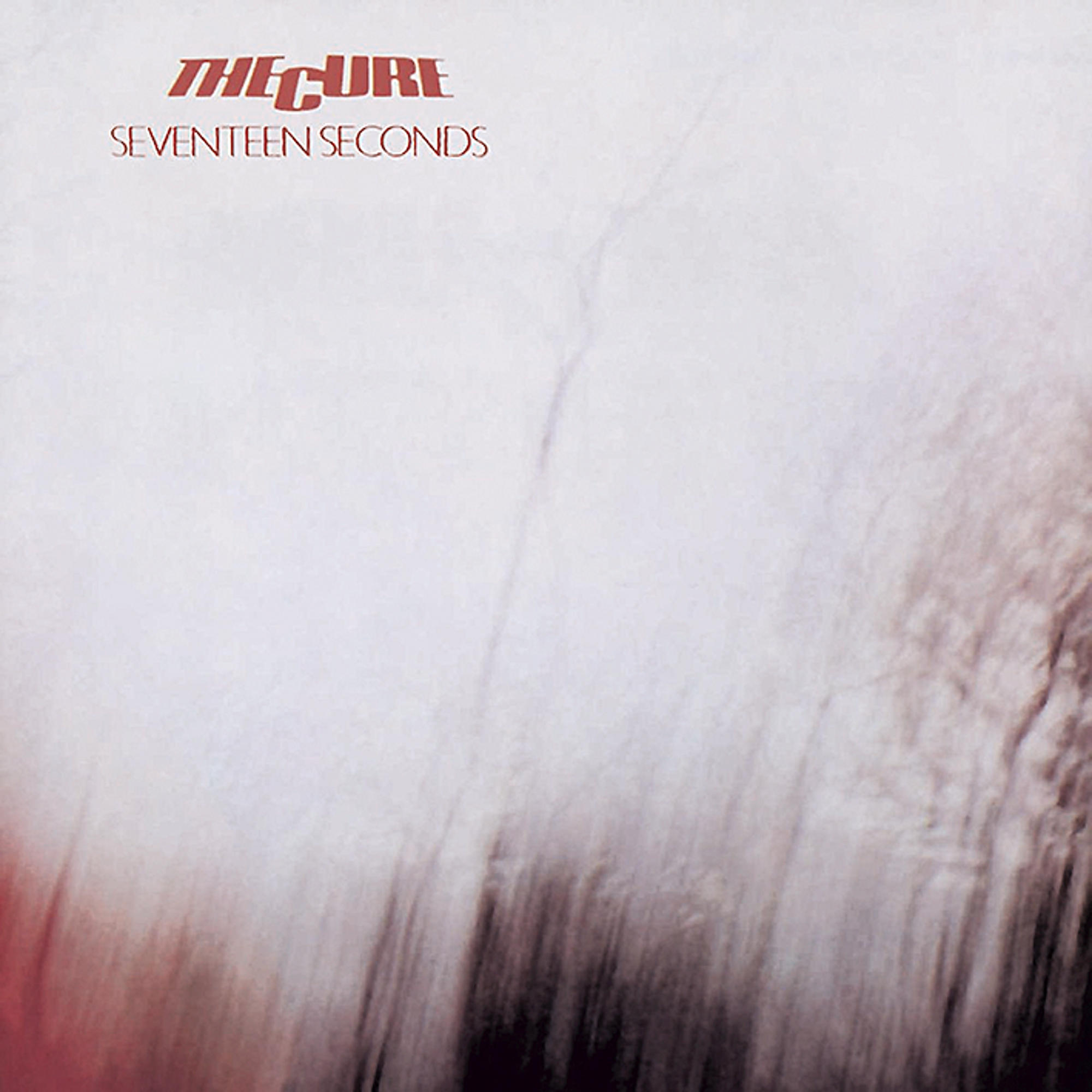 Pochette d'album avec un fond rouge et blanc flou. Le texte 'The Cure' est visible.