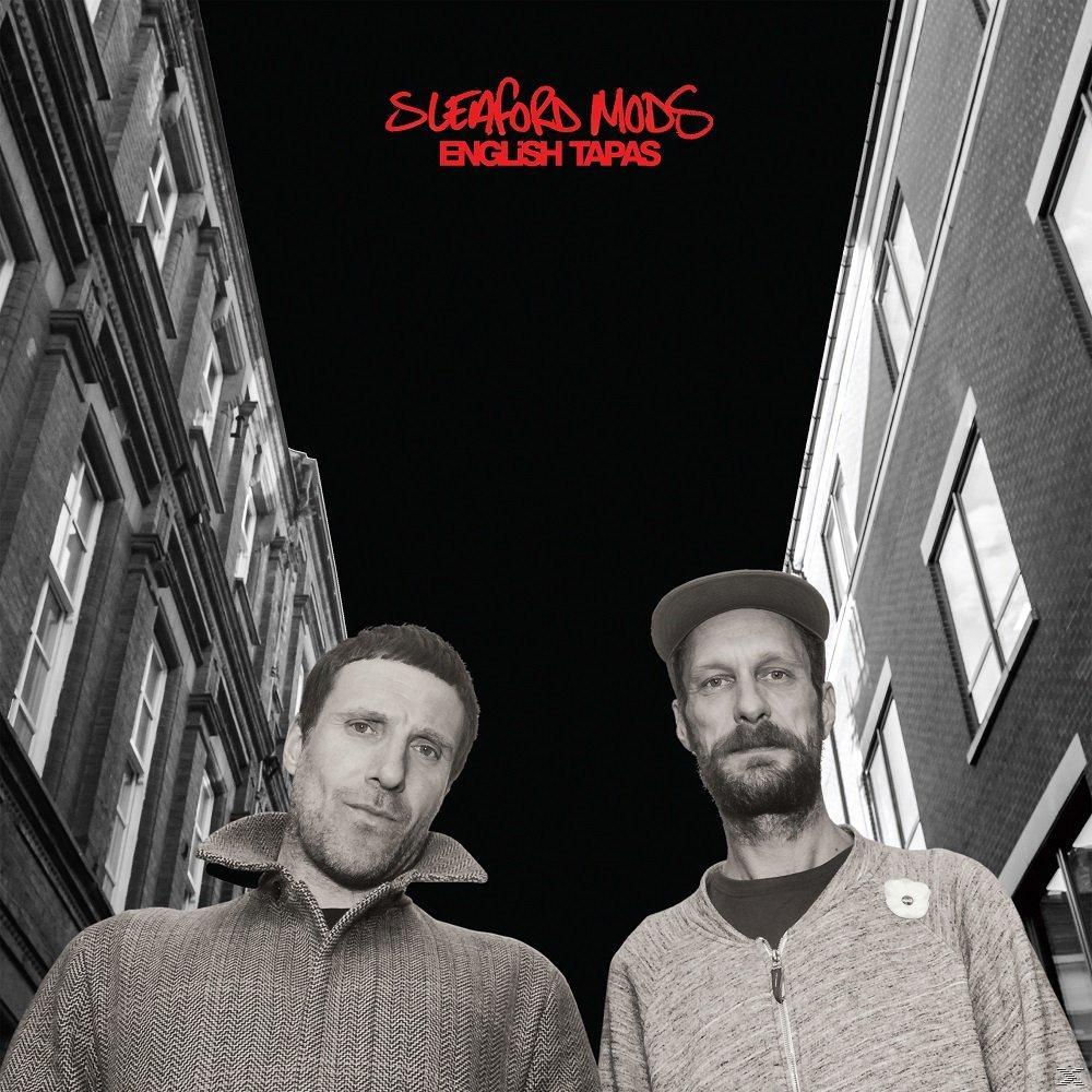 Albumcover mit zwei nach oben blickenden Männern zwischen Gebäuden, schwarzer Himmel, roter Text: Sleaford Mods, English Tapas.