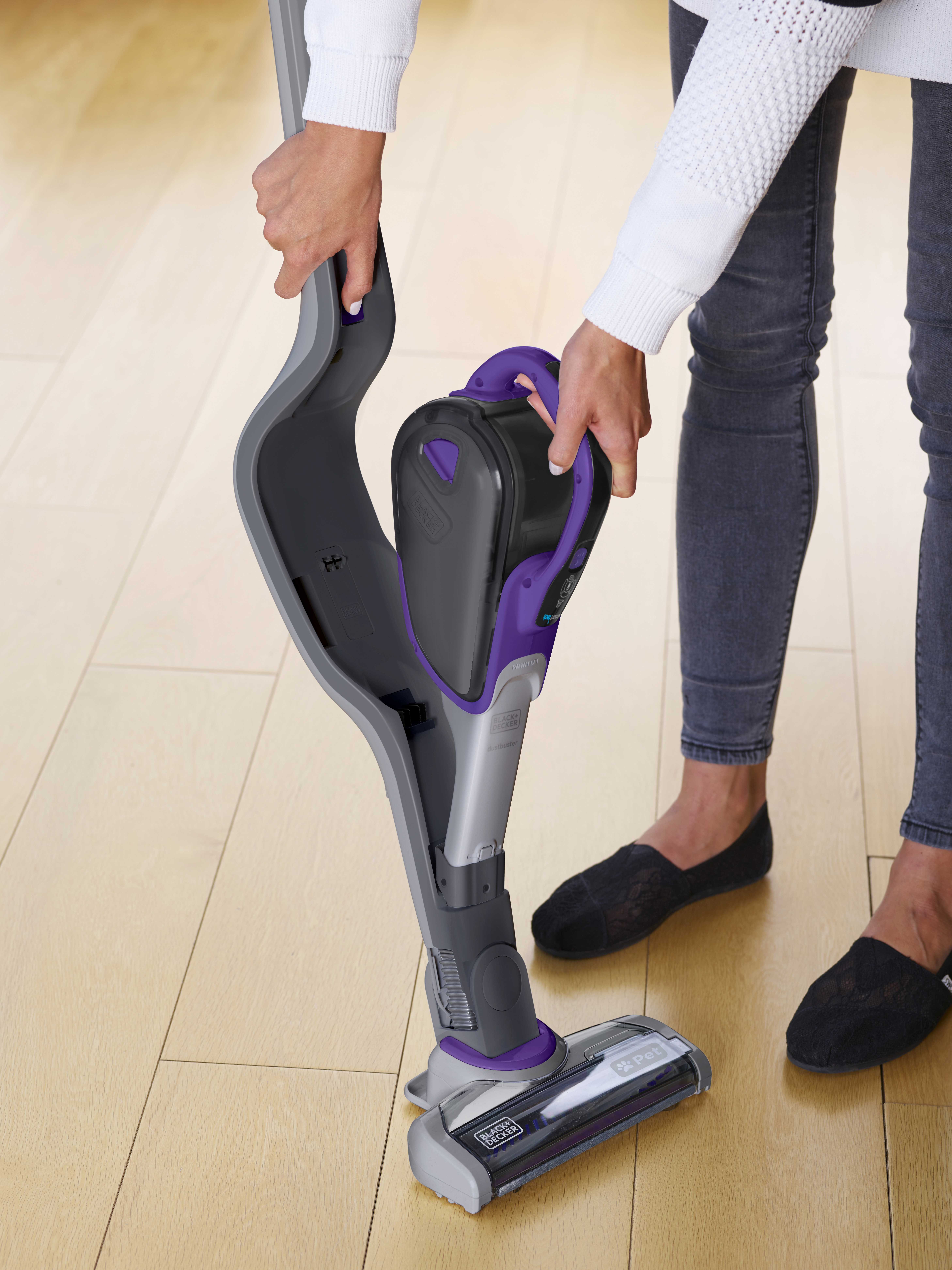 Eine Frau benutzt einen Black & Decker Staubsauger. Sie befindet sich in einem hellen Raum.