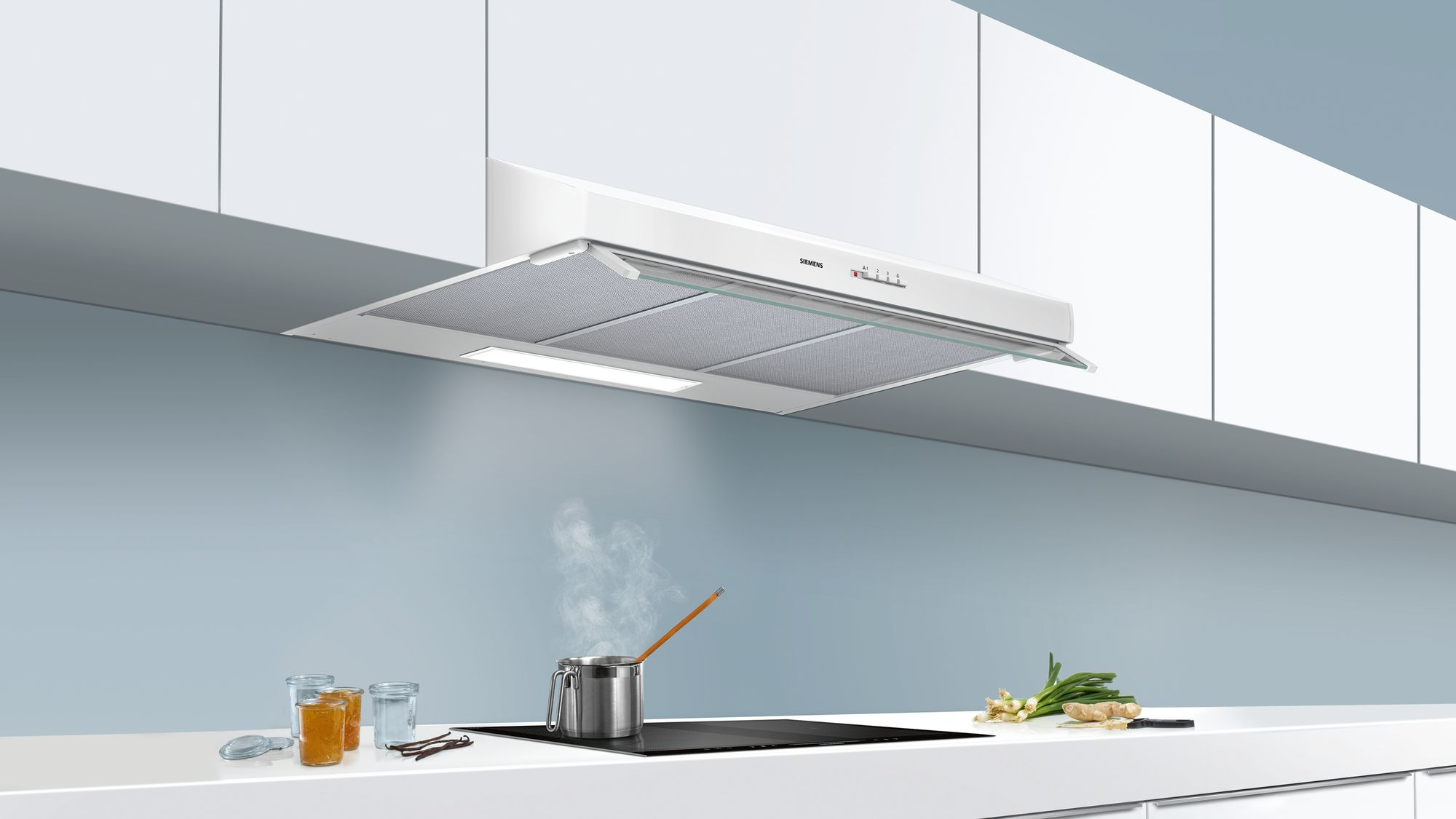 White kitchen hood, over a stove with steam coming from pot.