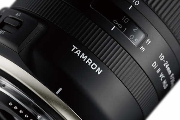 Close-up of a camera lens with 'TAMRON' branding and focus settings.