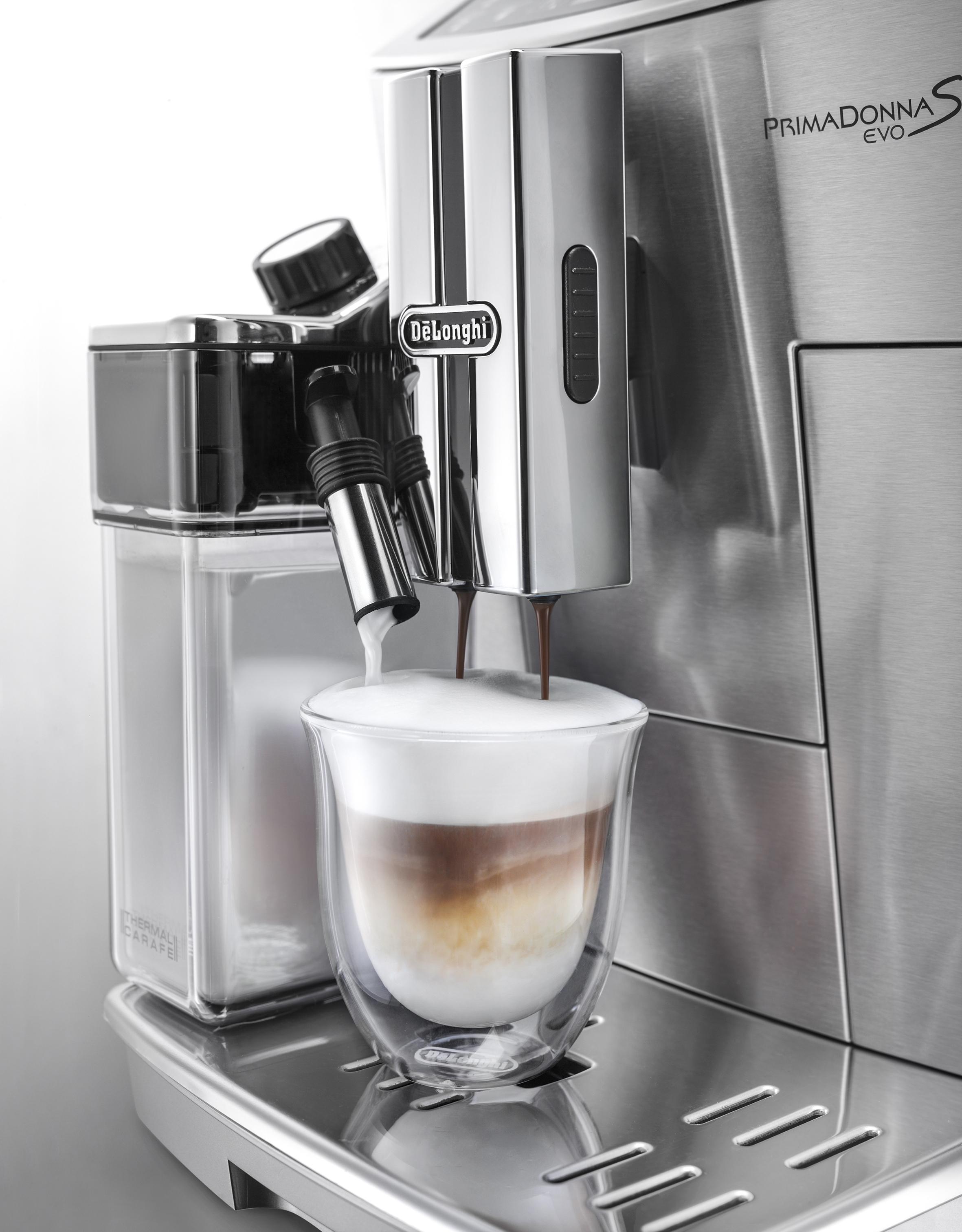 Kaffeemaschine, die Kaffee in ein Glas gießt. Milchbehälter an der Seite. Latte Art.