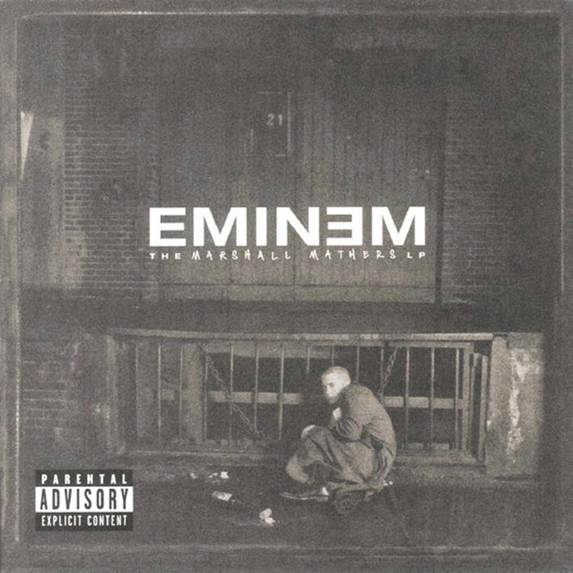 Albumcover von Eminem. Es zeigt einen Mann, der in einem dunklen Bereich sitzt, mit dem Schriftzug 'Eminem'.
