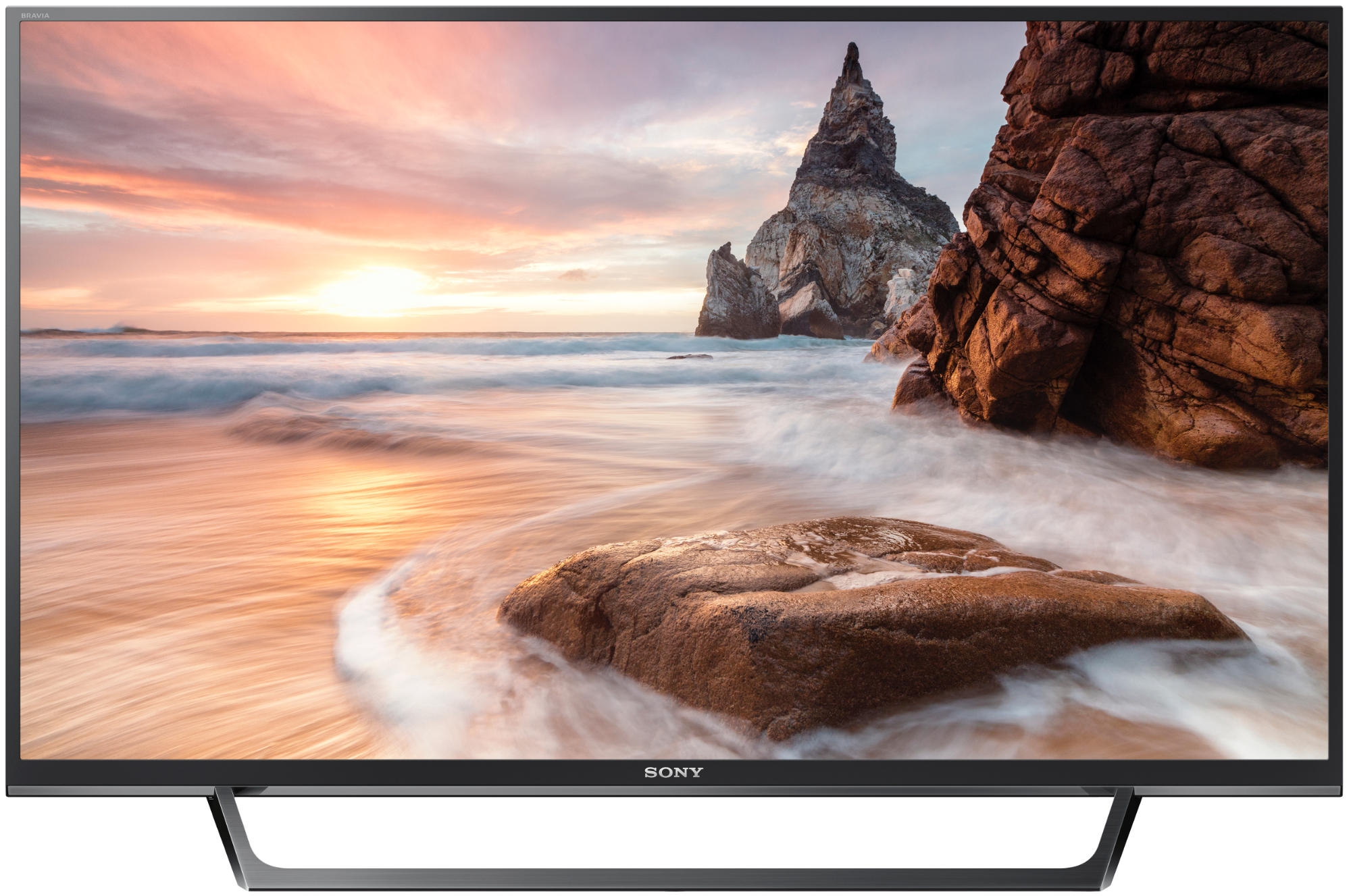Ein Breitbildfernseher zeigt eine Strandszene mit Sonnenuntergang, Felsen und Wellen. Sony-Logo unten.