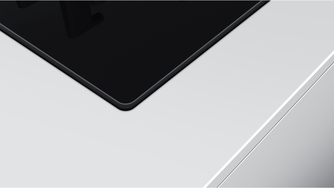 An angled view of a black, built-in cooktop on a white countertop.