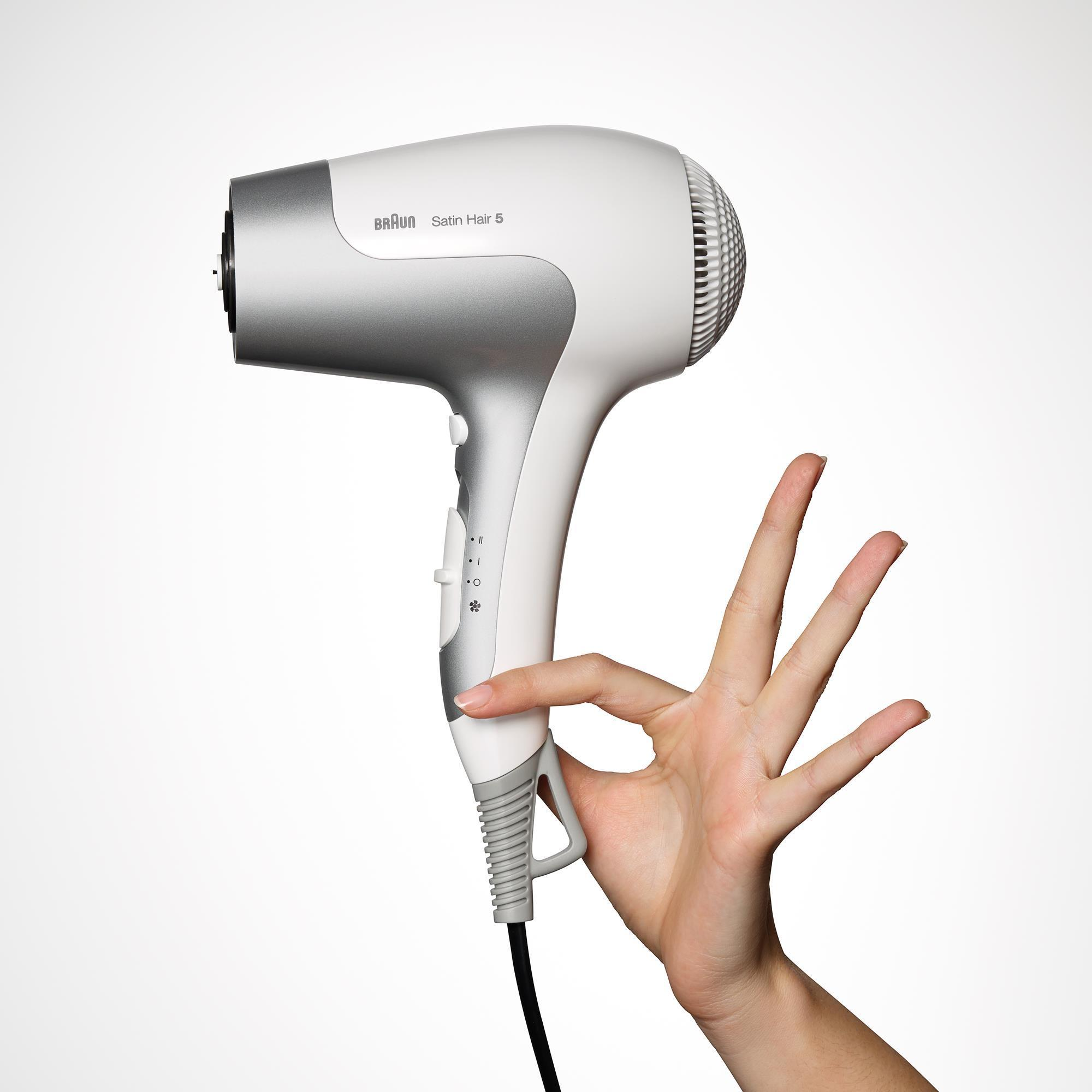 Weiß-silberner Braun Satin Hair 5 Föhn, gehalten von einer Hand, Finger ausgestreckt, isoliert auf Weiß.