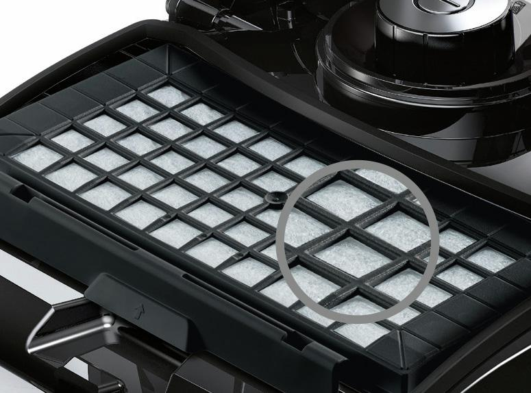 Close-up van een zwart stofzuigerfilter met een rasterpatroon. Het filter is omgeven door zwart plastic.