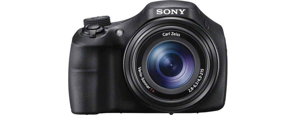 Schwarze Sony-Kamera, Vorderansicht. Carl Zeiss Objektiv und verschiedene Knöpfe und Räder. Weißer Hintergrund.