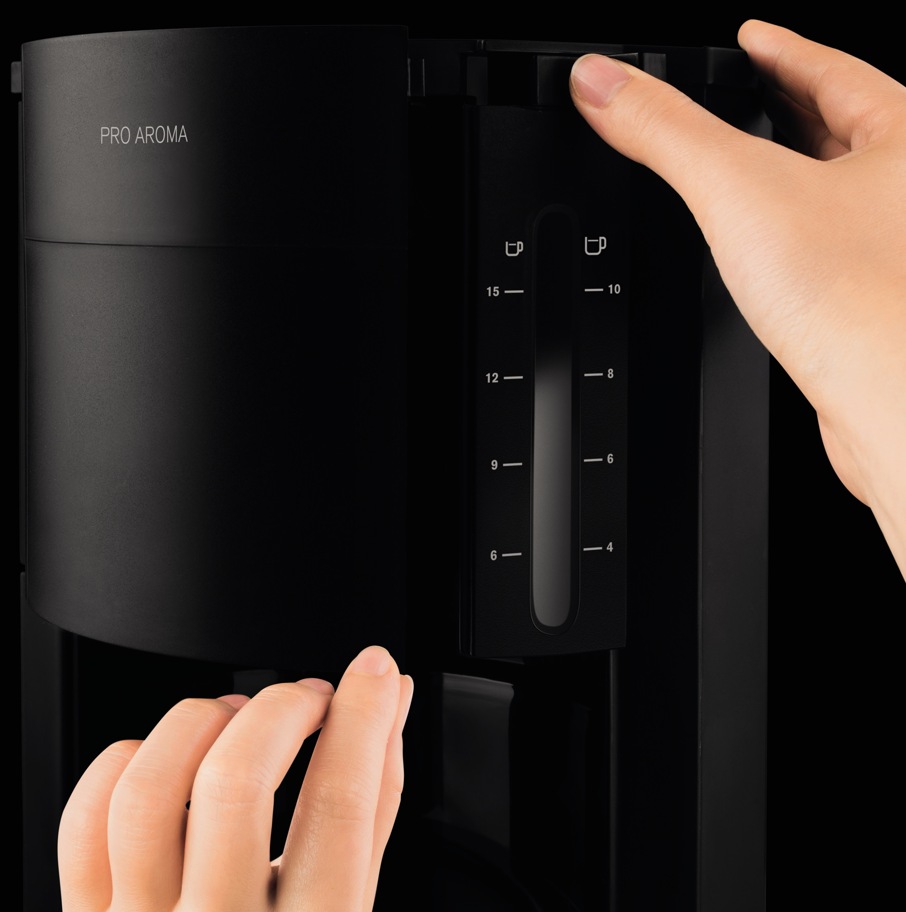 Coffee machine, black, with a hand pressing a button to set the cups.