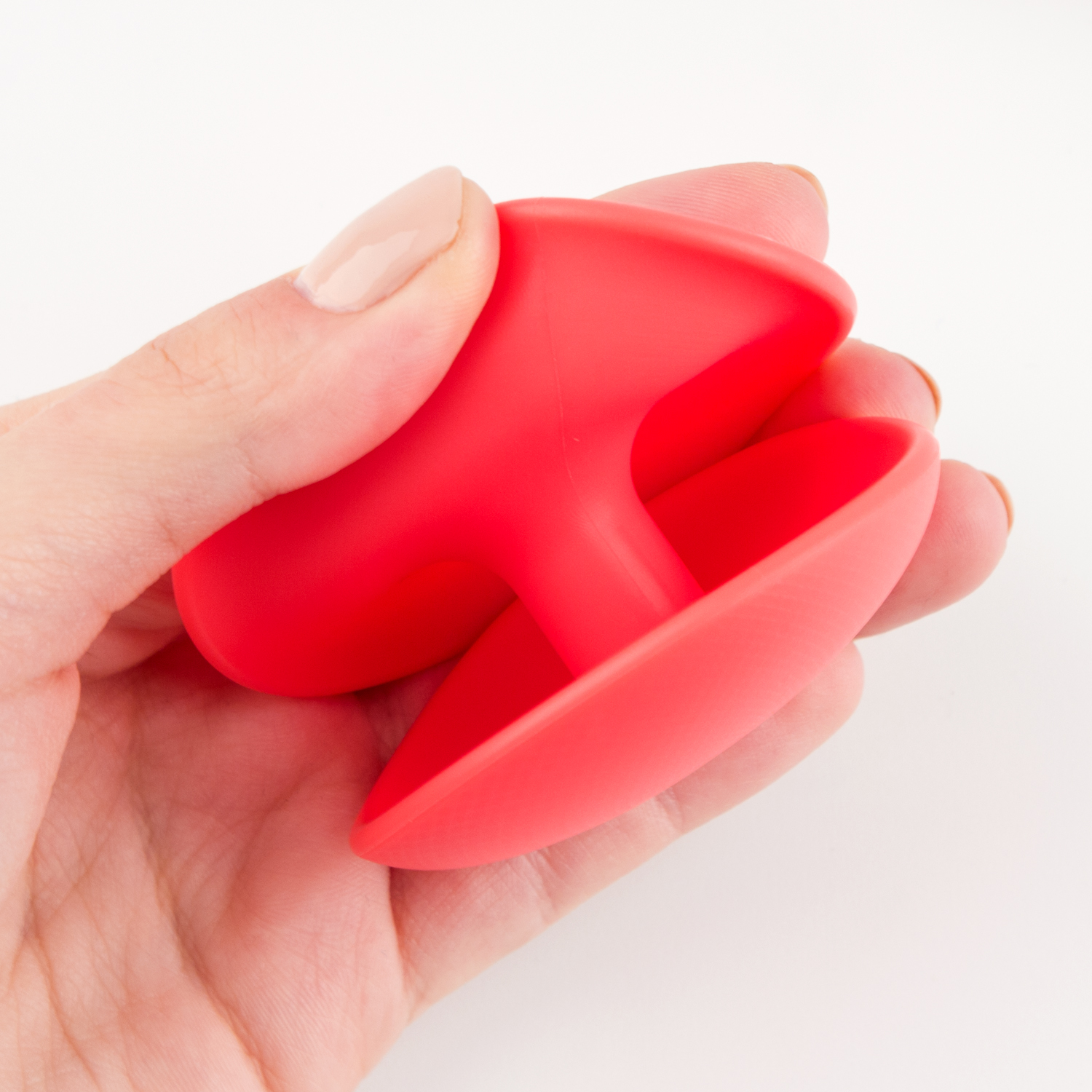 Eine Hand, die ein rotes medizinisches Gerät mit einer gebogenen Form vor weißem Hintergrund hält.