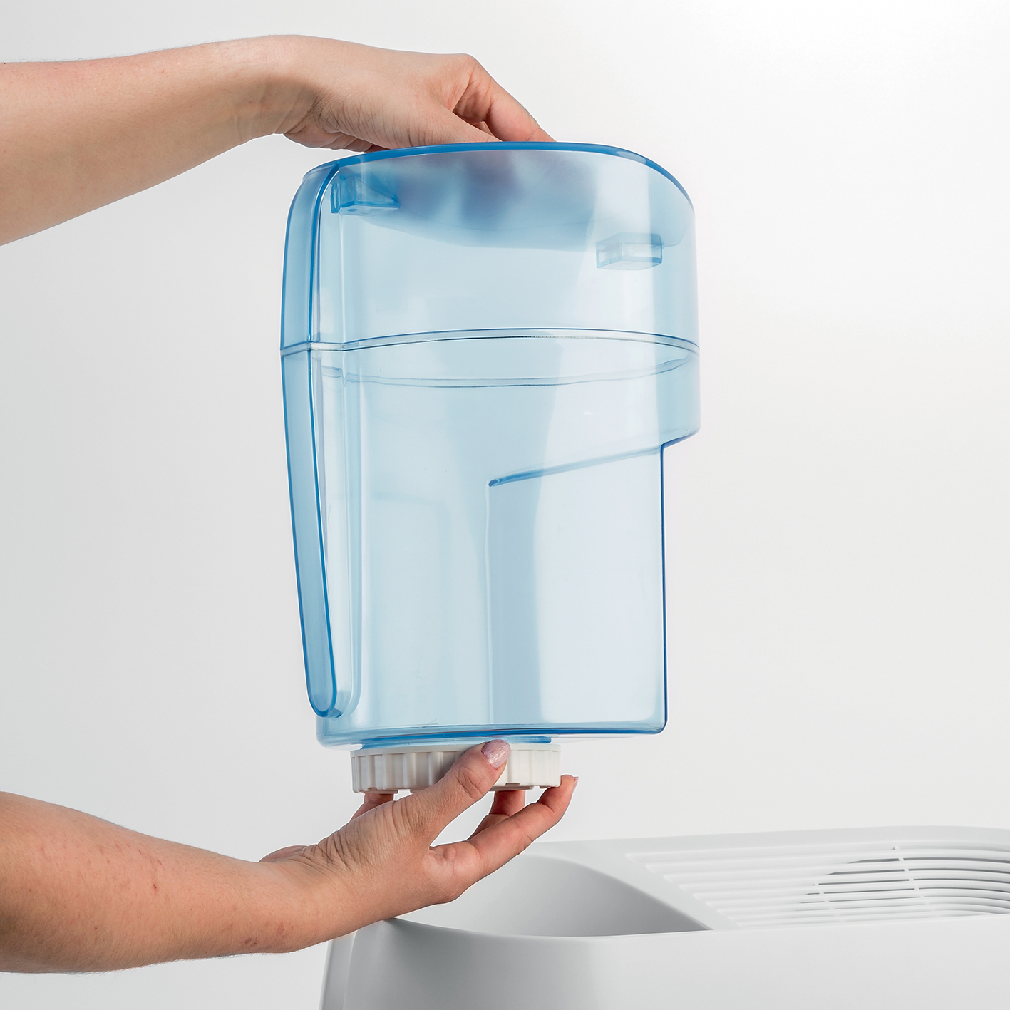 Hände halten einen durchscheinenden blauen Wassertank. Weißer Hintergrund.