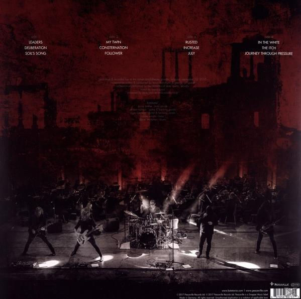 Albumcover. Band spielt auf der Bühne mit roter Beleuchtung.