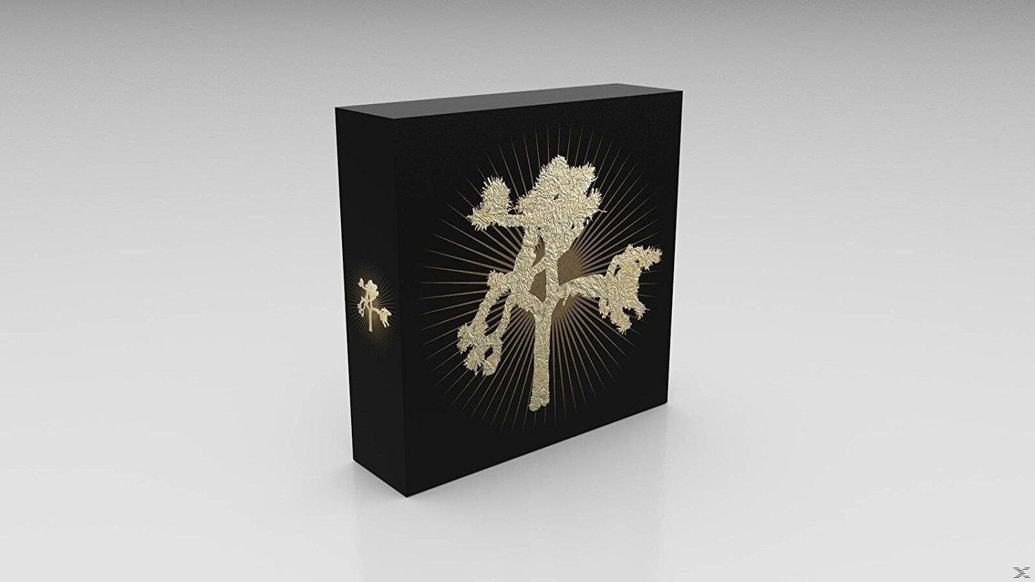 Schwarze Box mit goldenem Baumdesign und Sonnenstrahlen. Das Albumcover von The Joshua Tree.