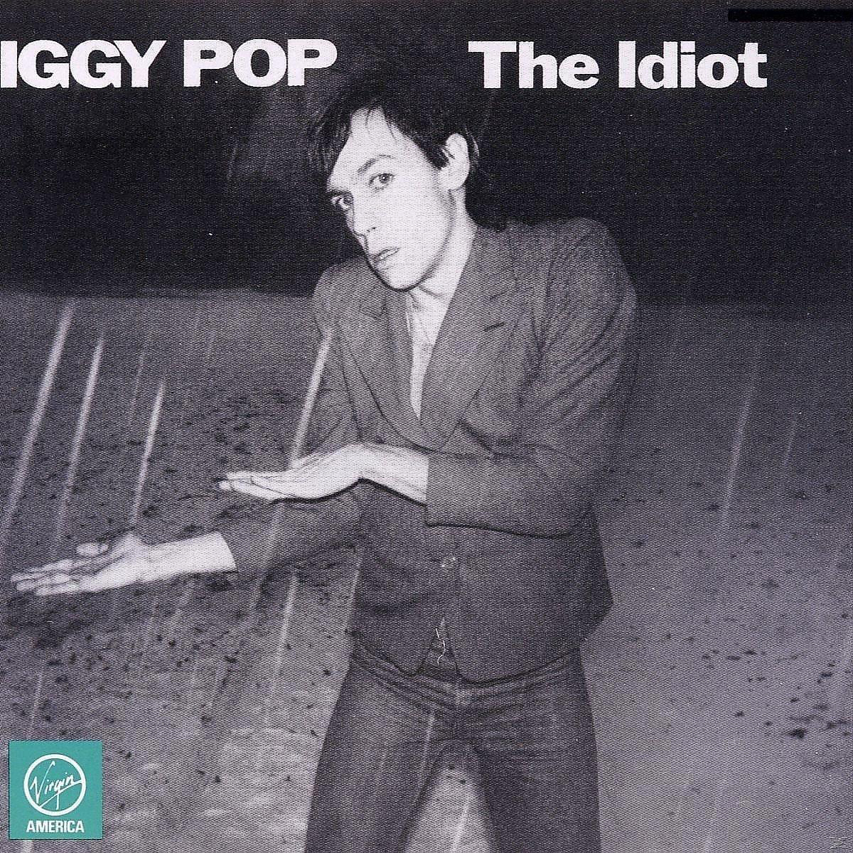 Iggy Pop auf dem Albumcover von The Idiot. Er trägt einen Anzug, der Arm ist ausgestreckt.